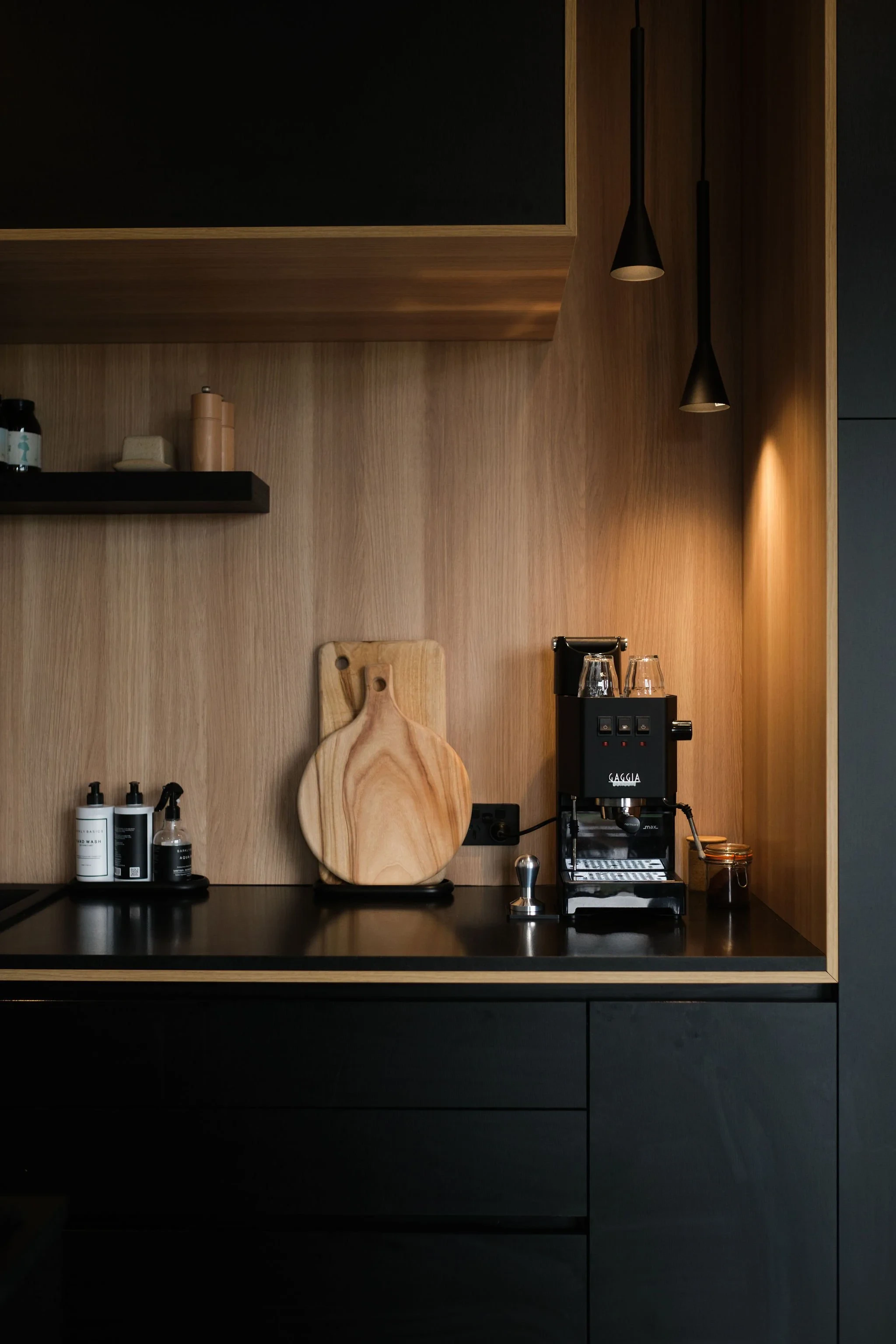 Kitchen counter with coffee machine and wooden cutting board in a modern, minimalist kitchen