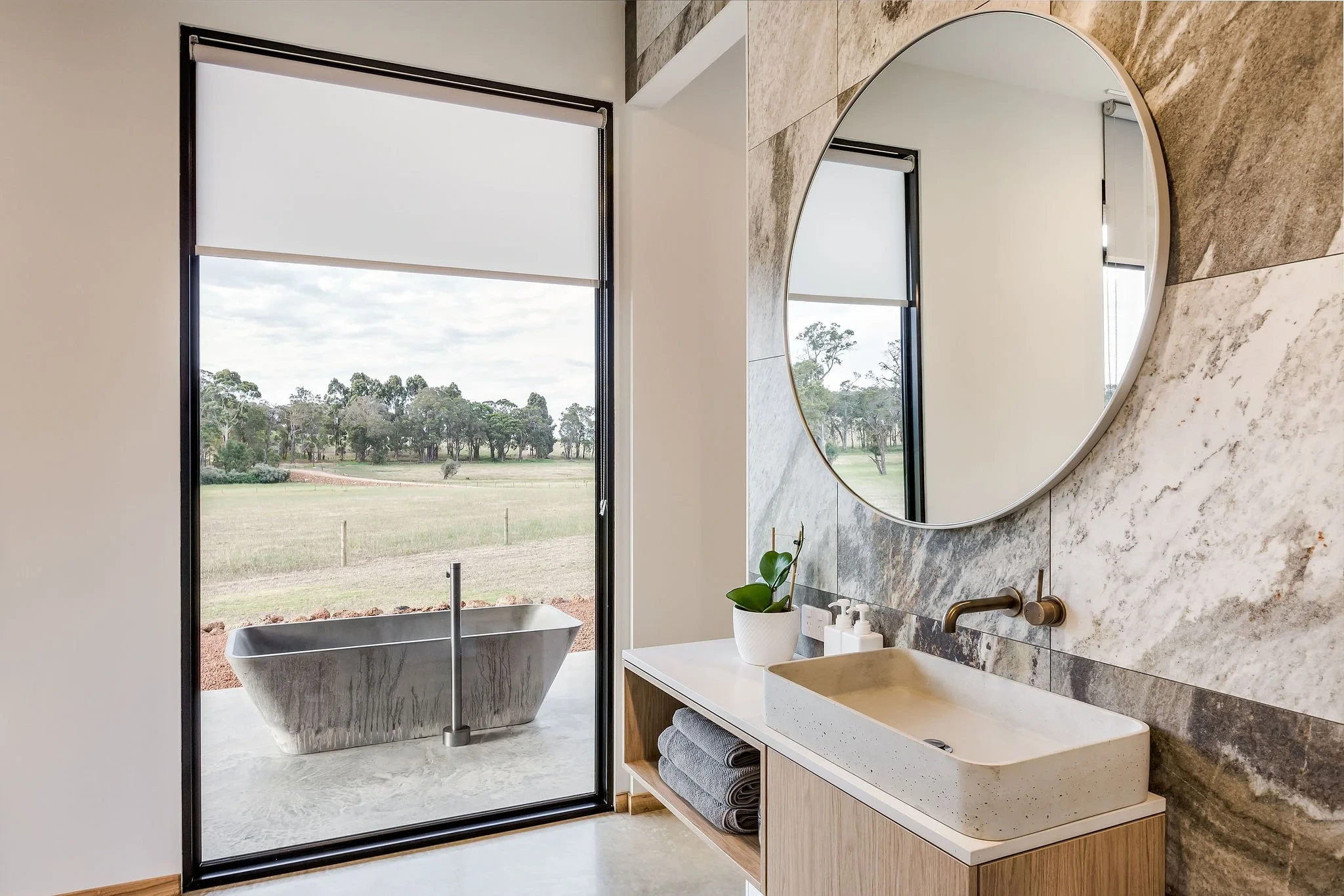 Bathroom with freestanding bathtub overlooking a garden through large glass window
