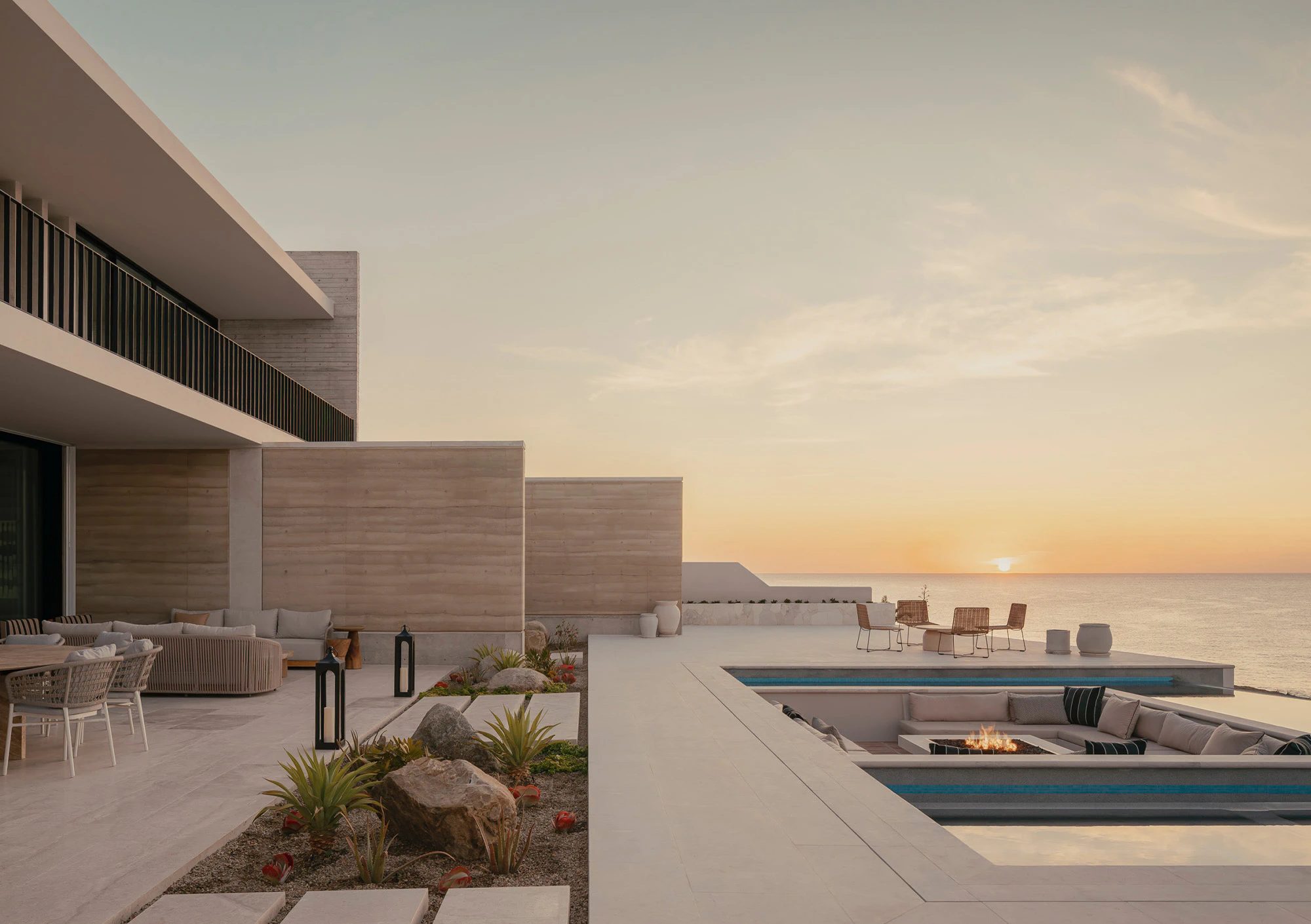 Luxury poolside terrace overlooking ocean at sunset
