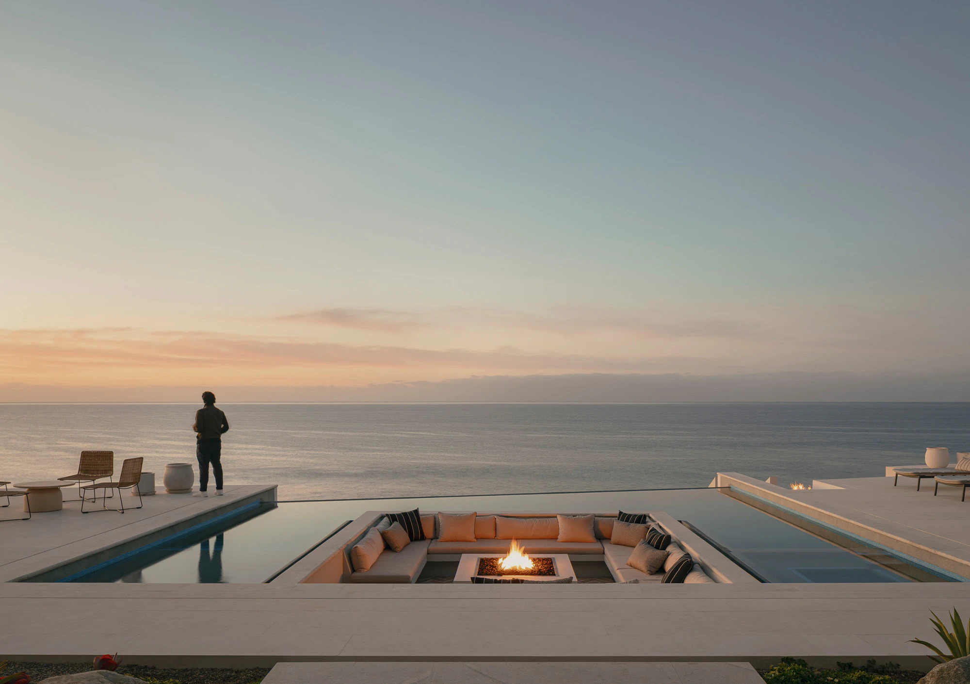 Outdoor pool area overlooking the ocean at sunset