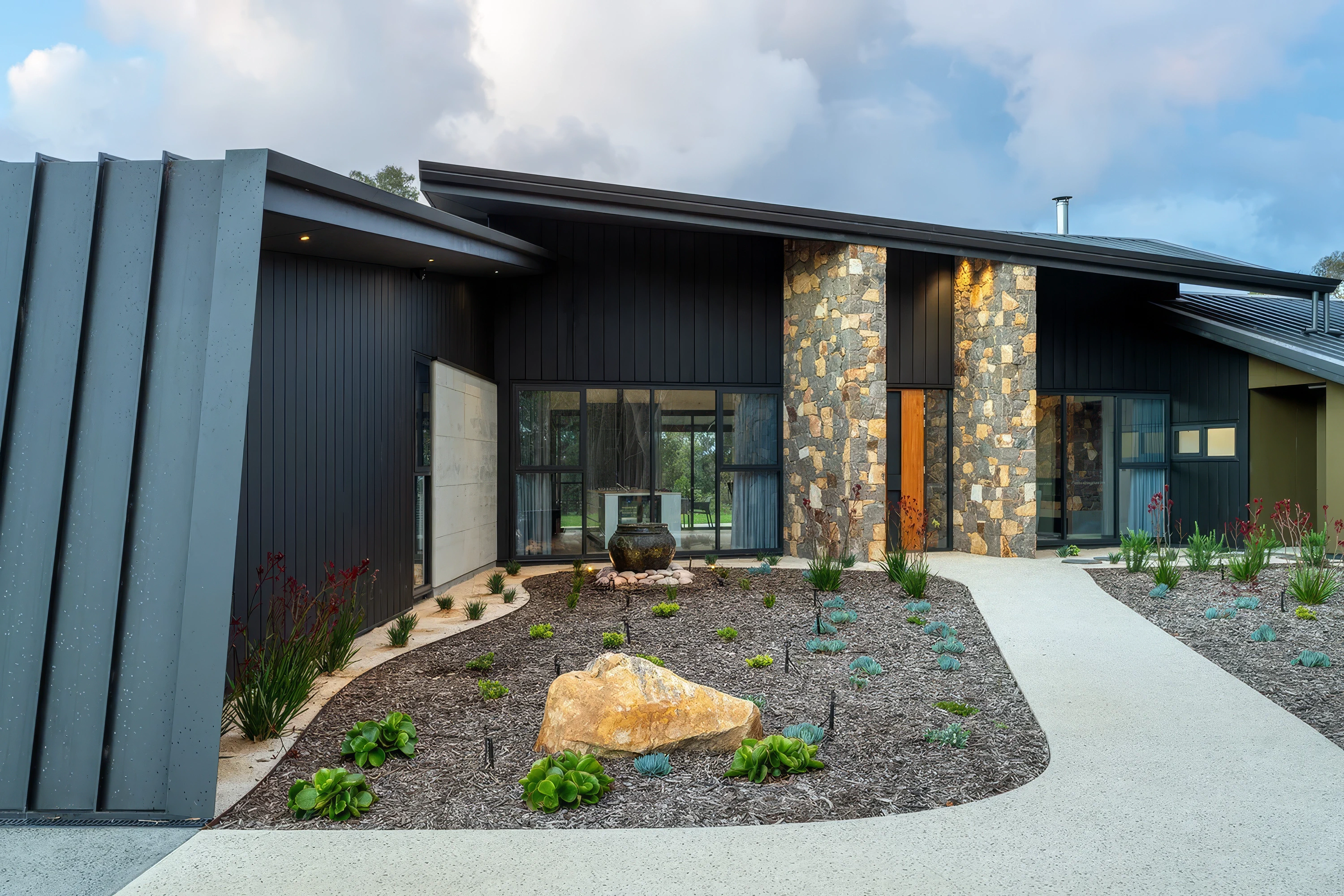 Contemporary house exterior featuring stone façade and native garden landscaping