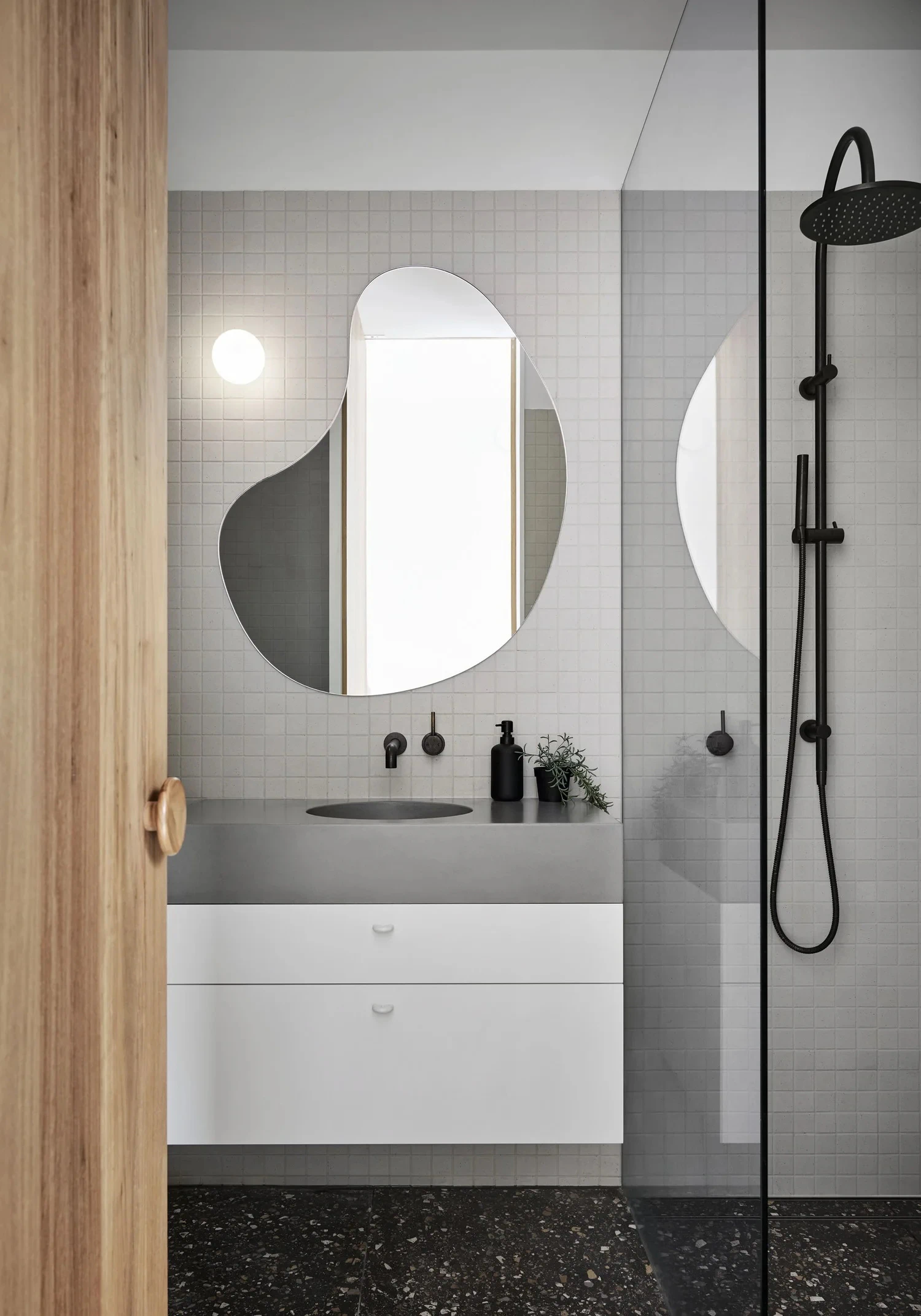 Bathroom vanity, tiled shower and irregular mirror