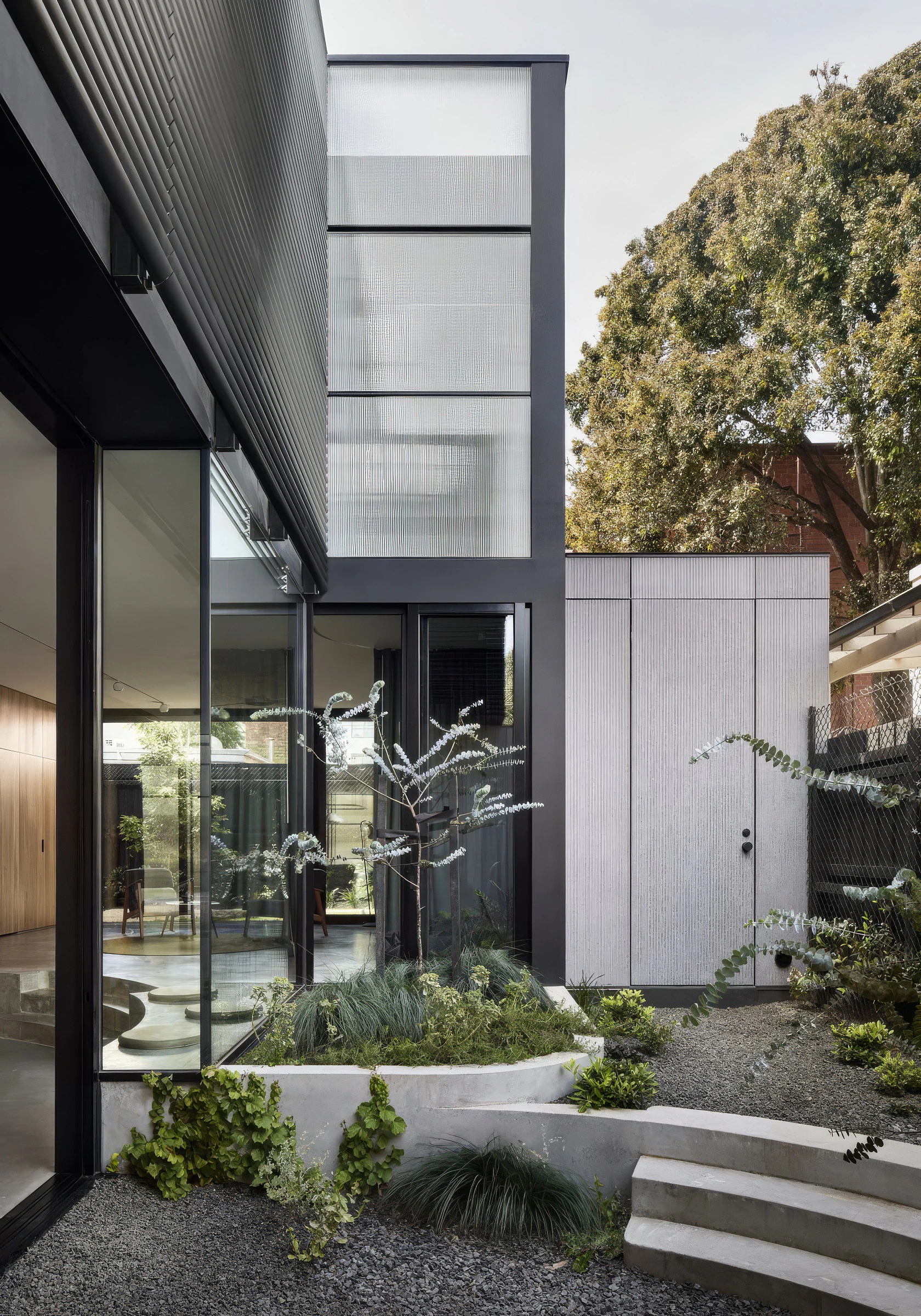 House courtyard featuring fluted glass walls, curved concrete steps and garden beds