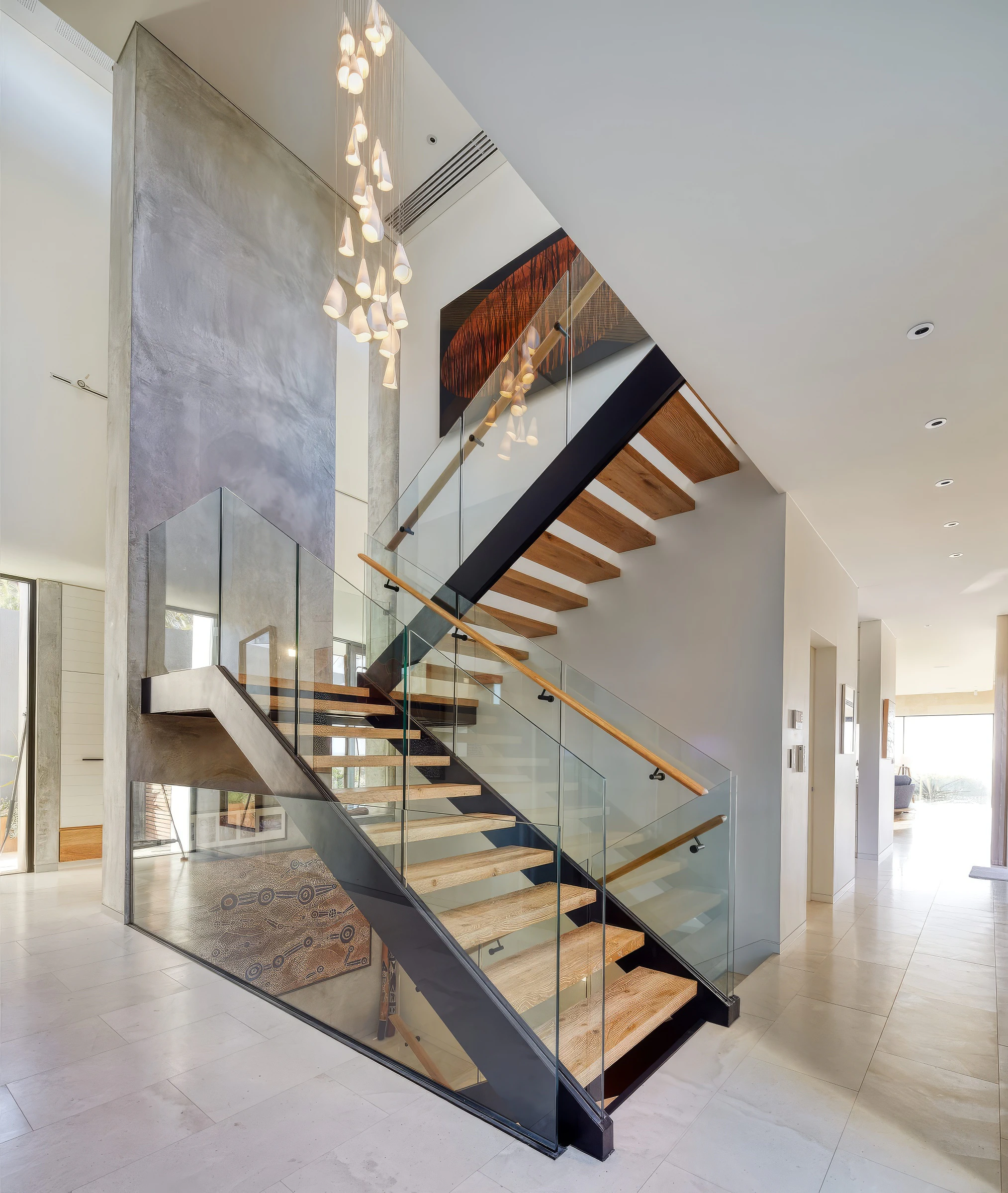 Open timber staircase and pendant lights in double-height entry hall
