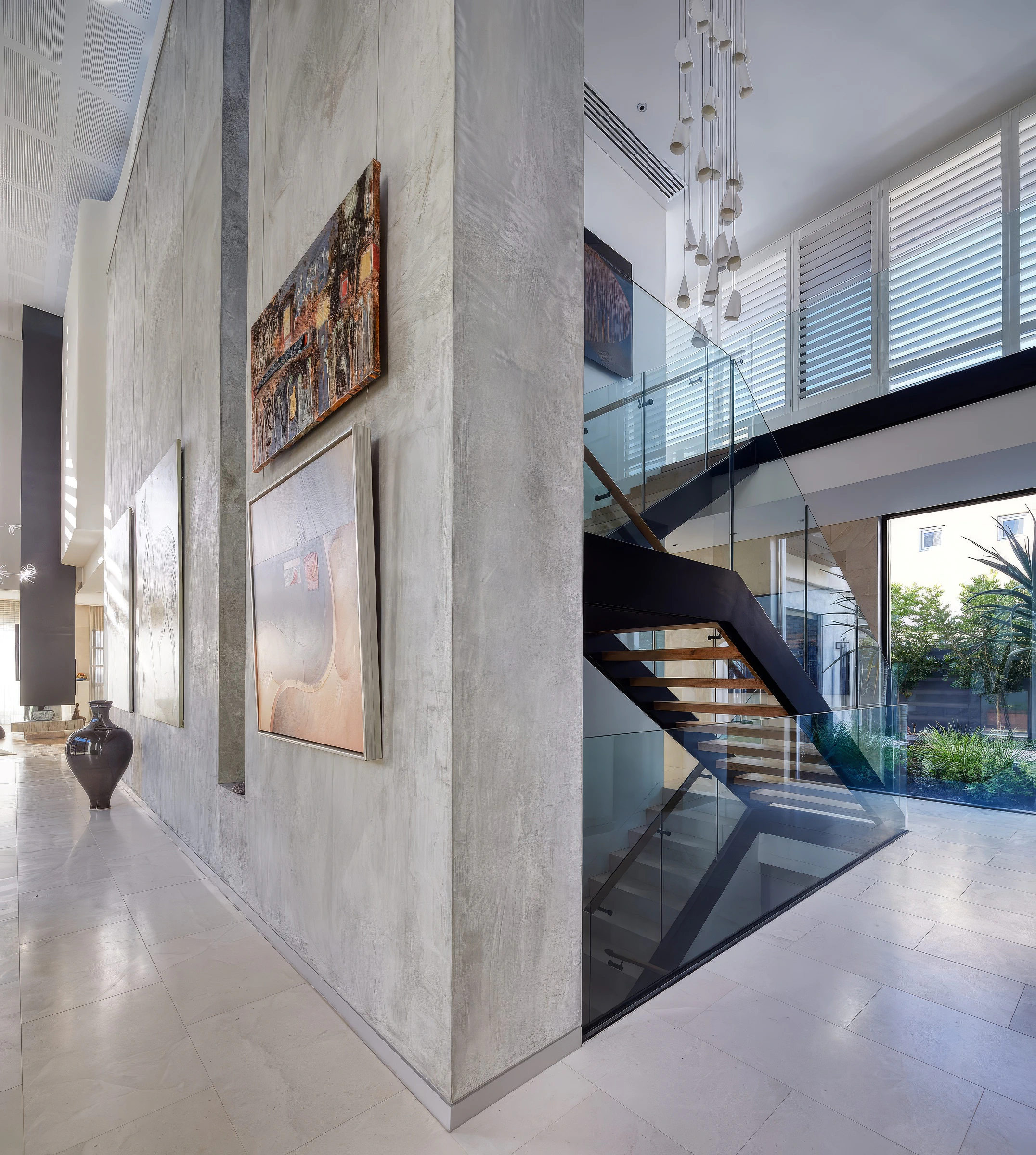 Double-height foyer and staircase with glass balustrade and wall art