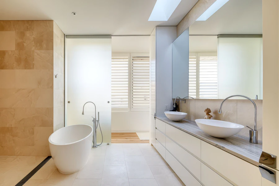Freestanding bath and double vanity in tiled bathroom