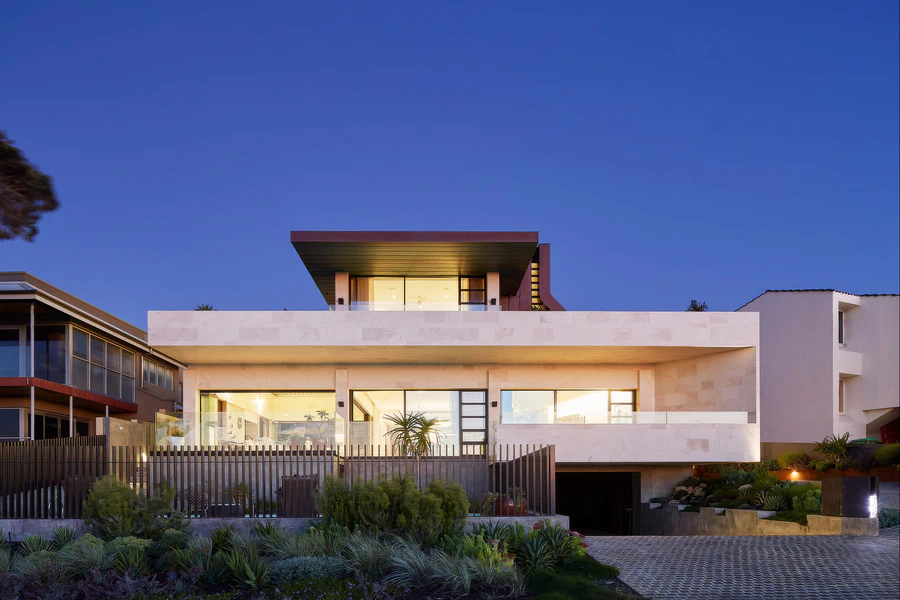 Two-storey house facade at dusk with balcony and garage entrance