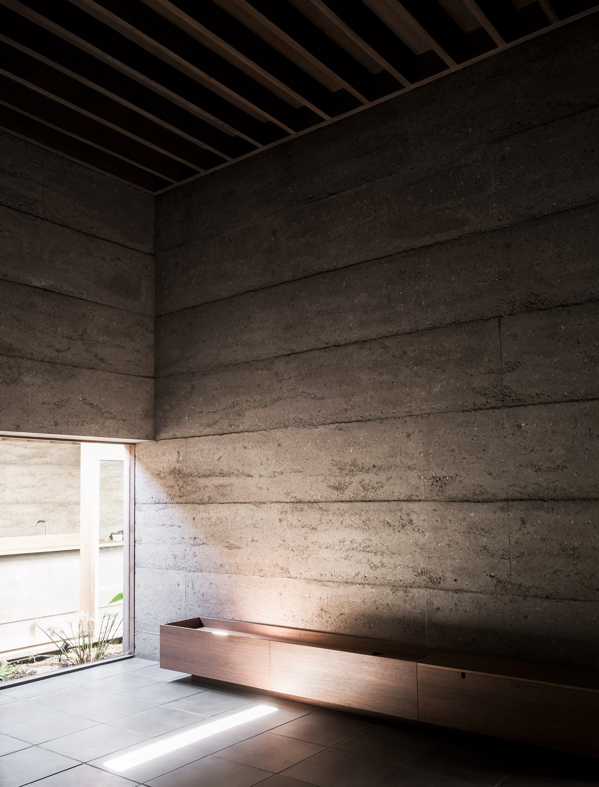 Concrete interior wall and wooden bench in sunlit room
