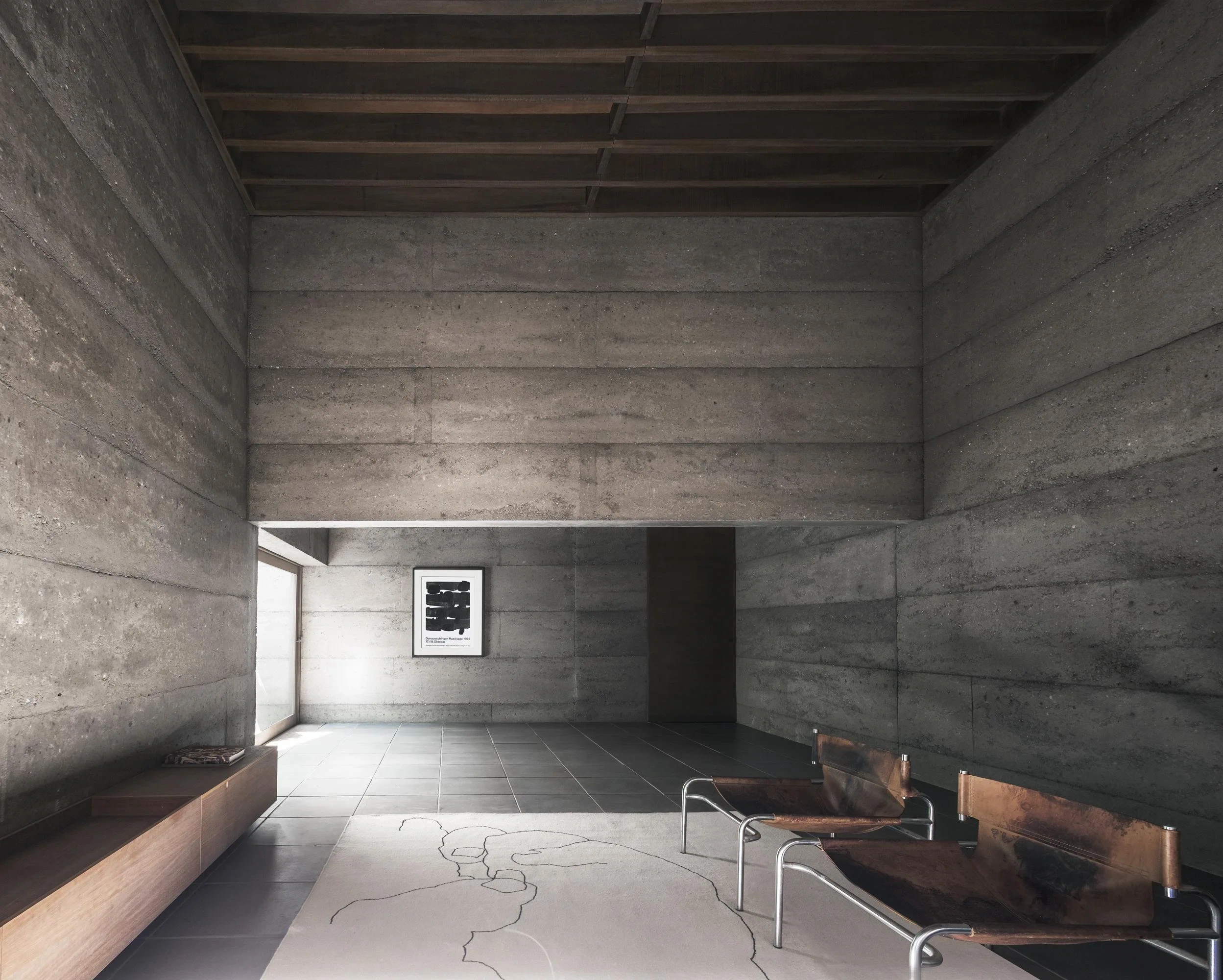 Concrete interior room featuring bench seating, minimalist chairs and tiled floor