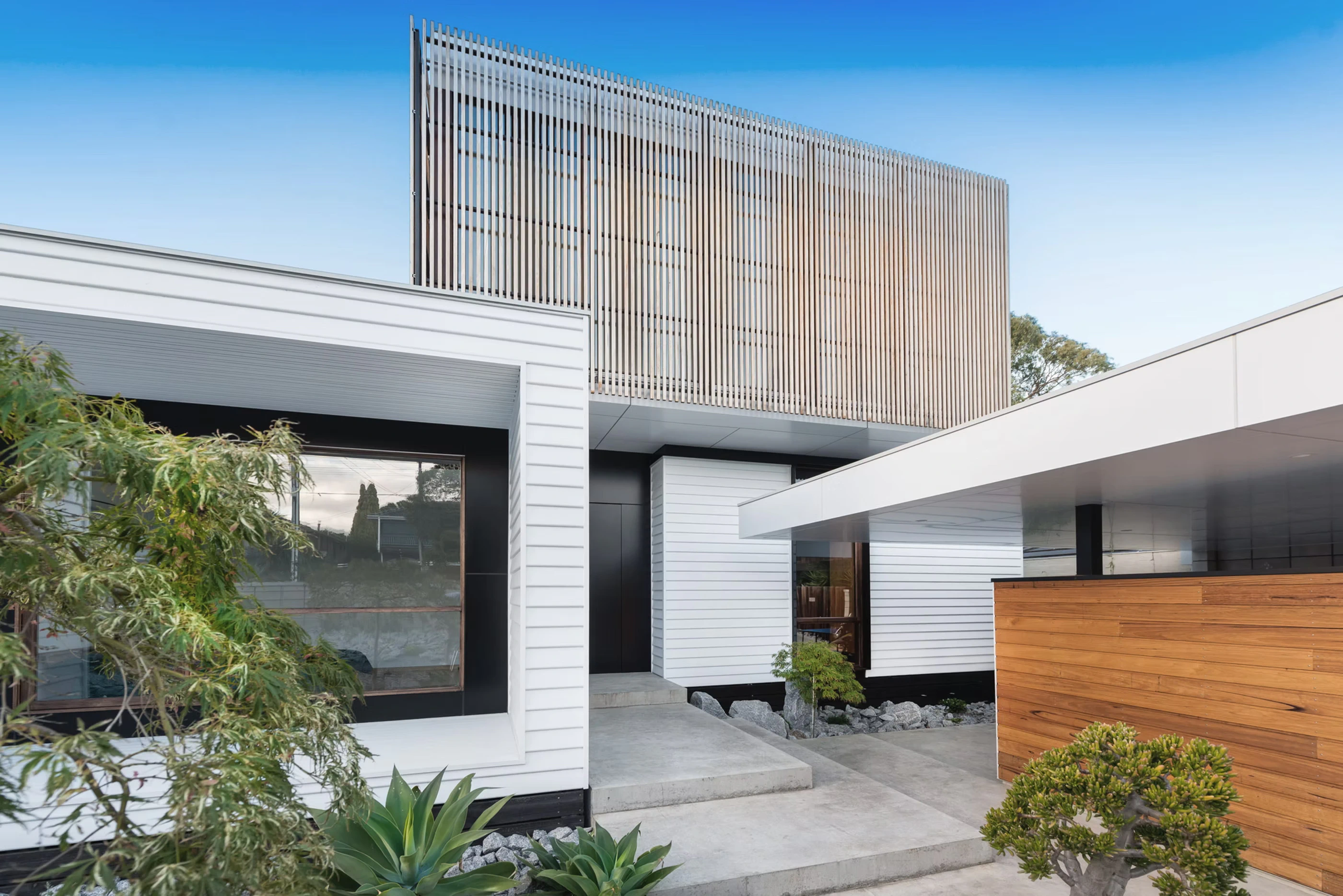 Estelle Residence with white cladding, black trim, and wooden accents