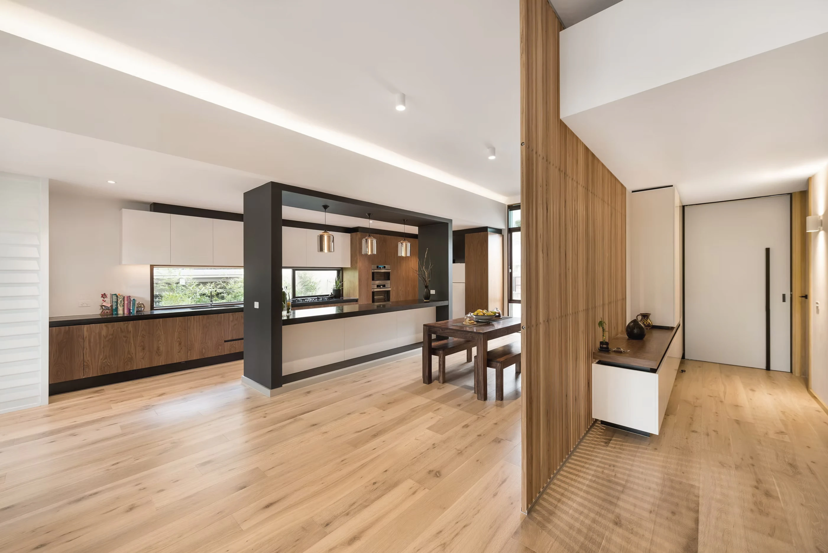 Open-plan kitchen and dining area with natural wood accents and minimalist design