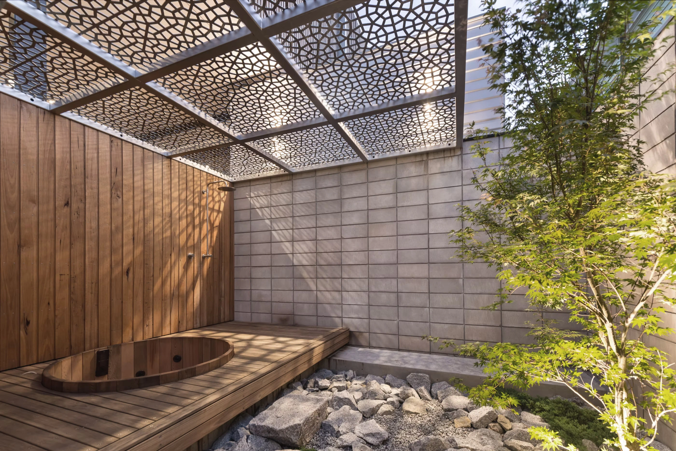 Japanese-style outdoor zen bath area with wooden tub and stone landscaping