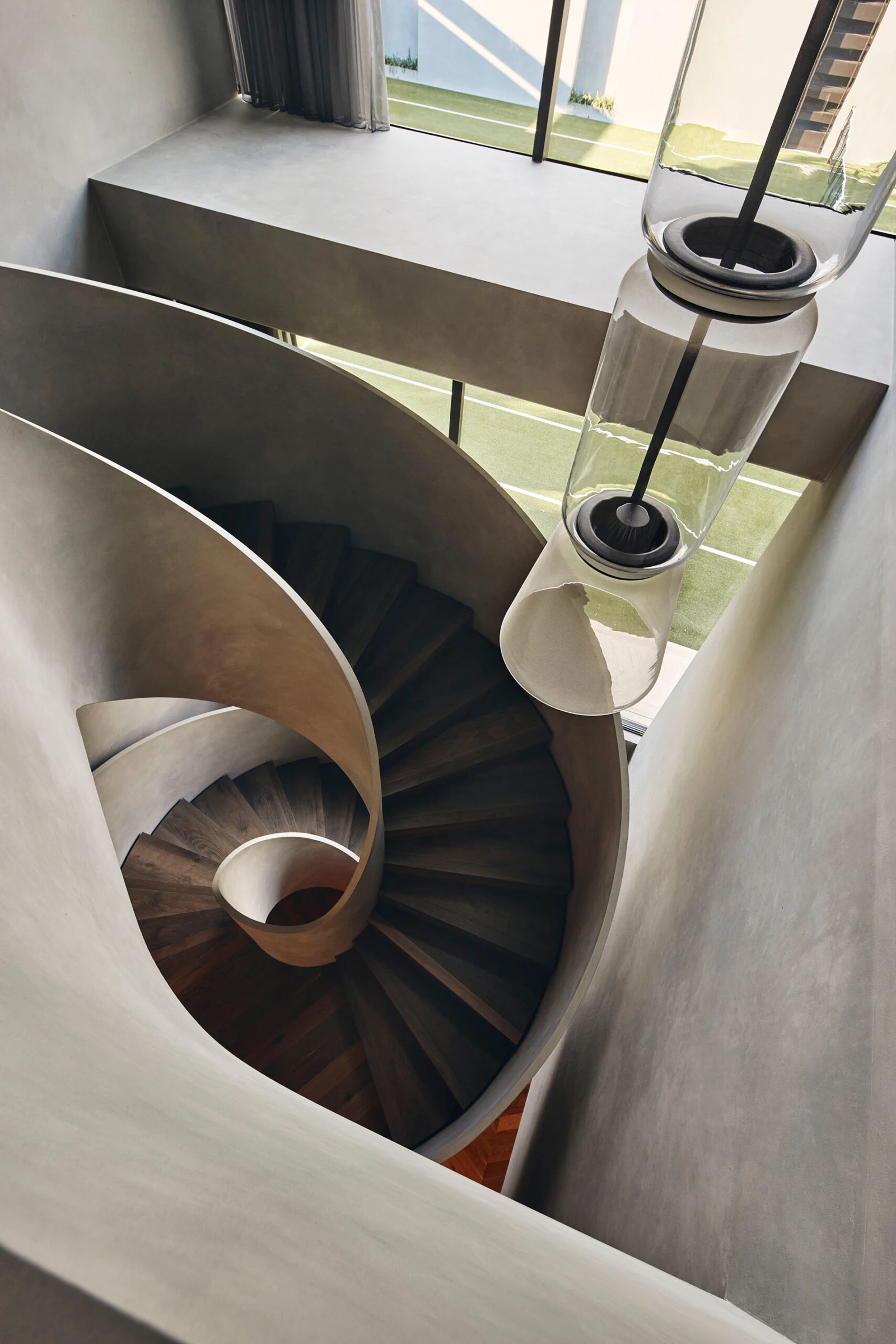 Curved concrete staircase and dark timber treads beneath glazing