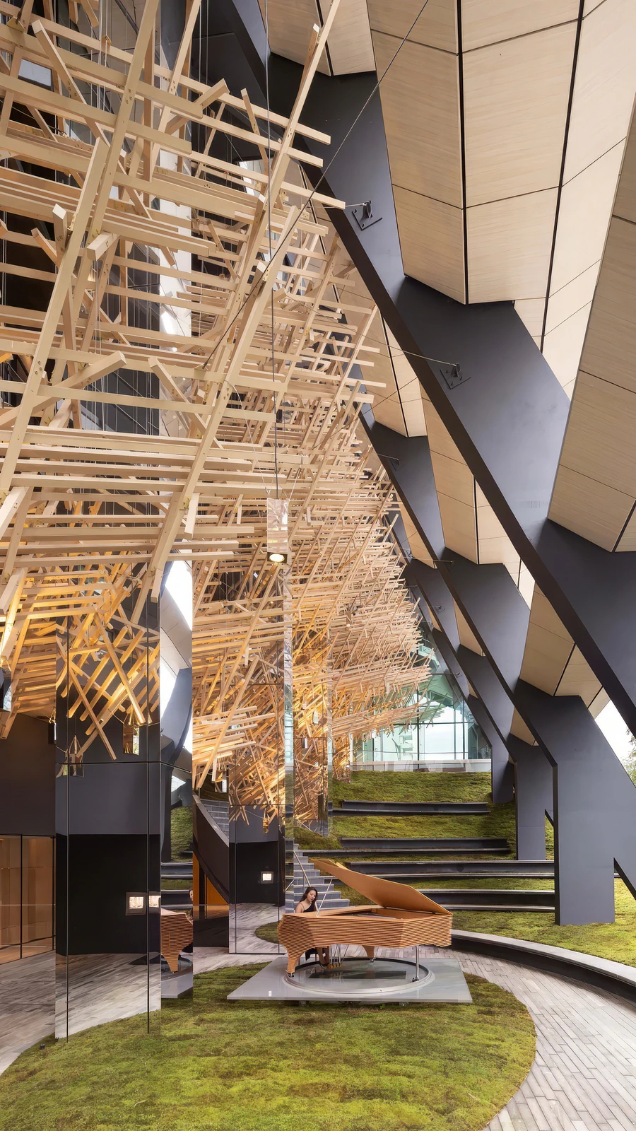 Architectural interior featuring wooden lattice ceiling, grand piano, and tiered seating on green flooring