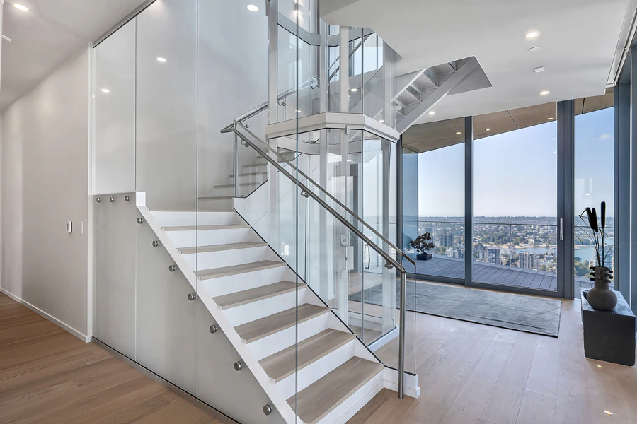 An open bleached white oak staircase and a private glass elevator