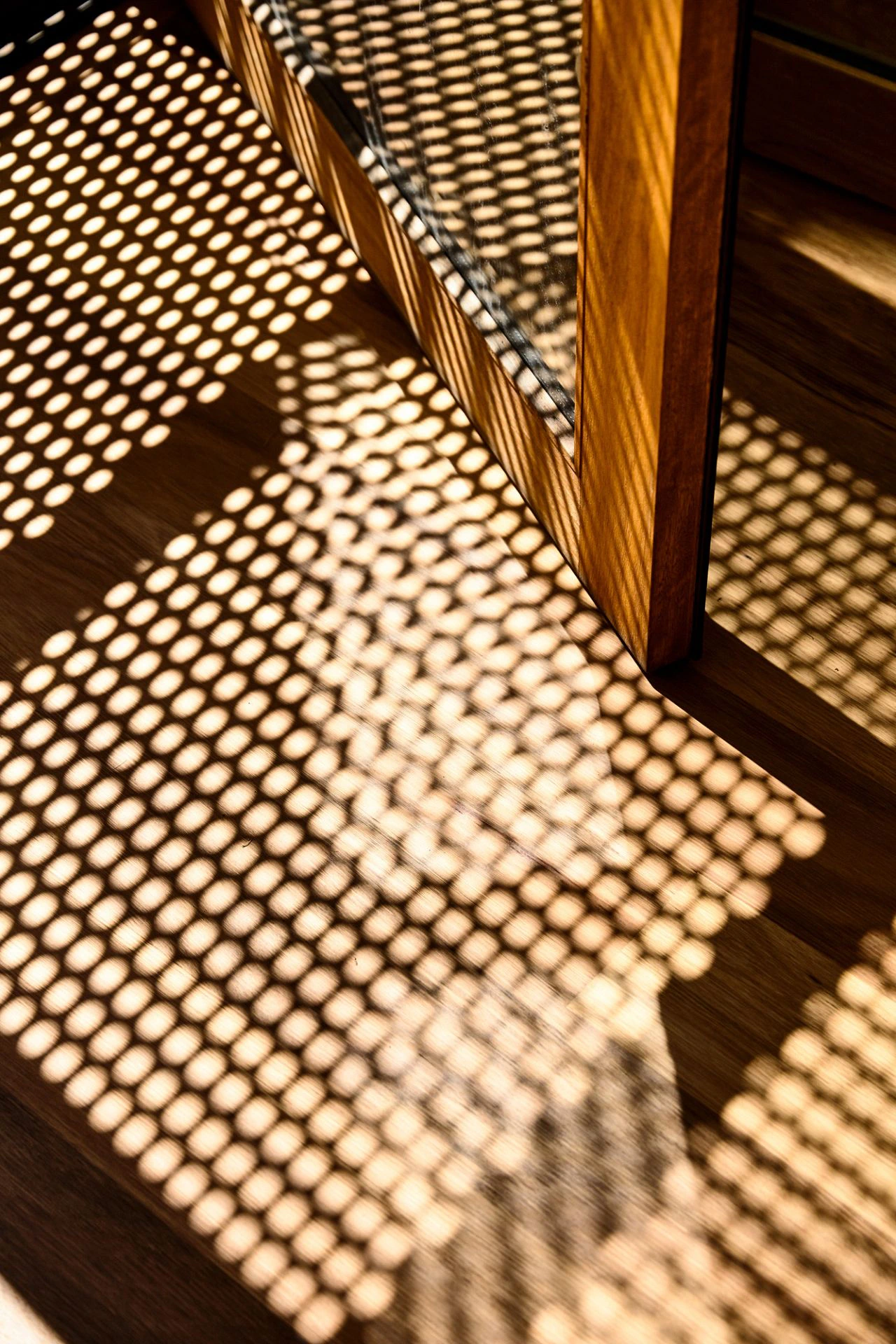 Perforated screen shadows across timber floor at Seaberg beach house