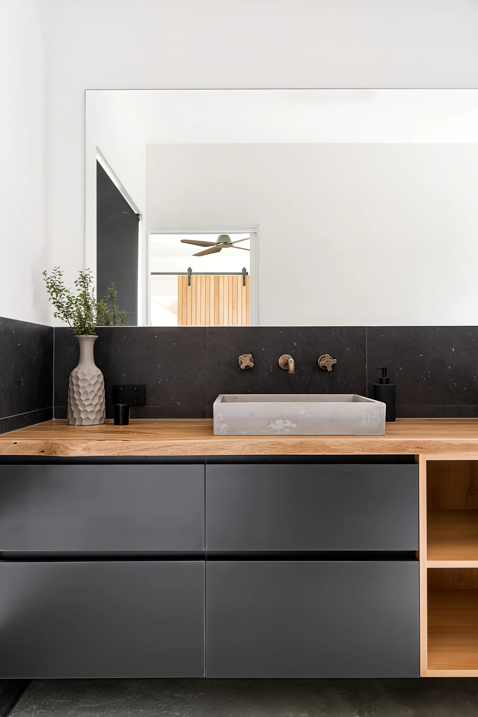 Bathroom vanity with black drawers, wooden countertop, concrete sink, and decorative vase