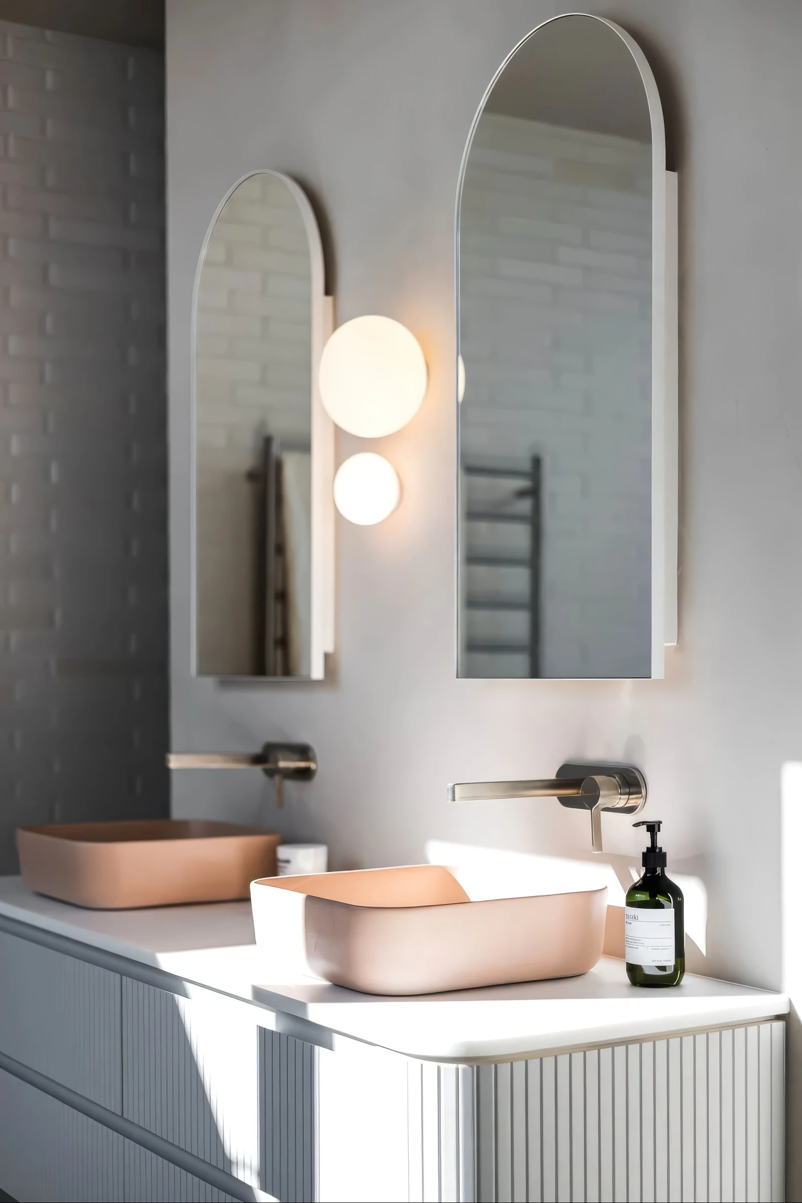 Peach concrete basins and arched bathroom mirrors