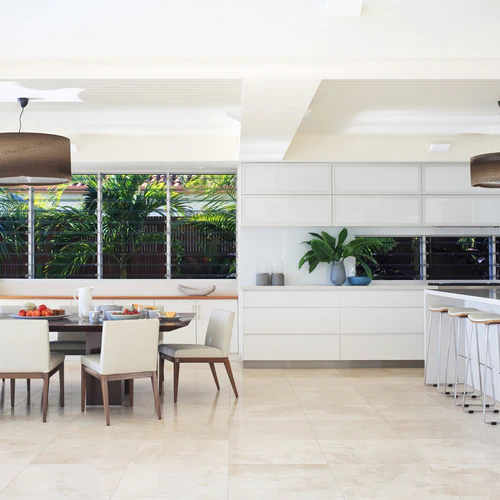 Modern white kitchen and dining area with large window and bar stools