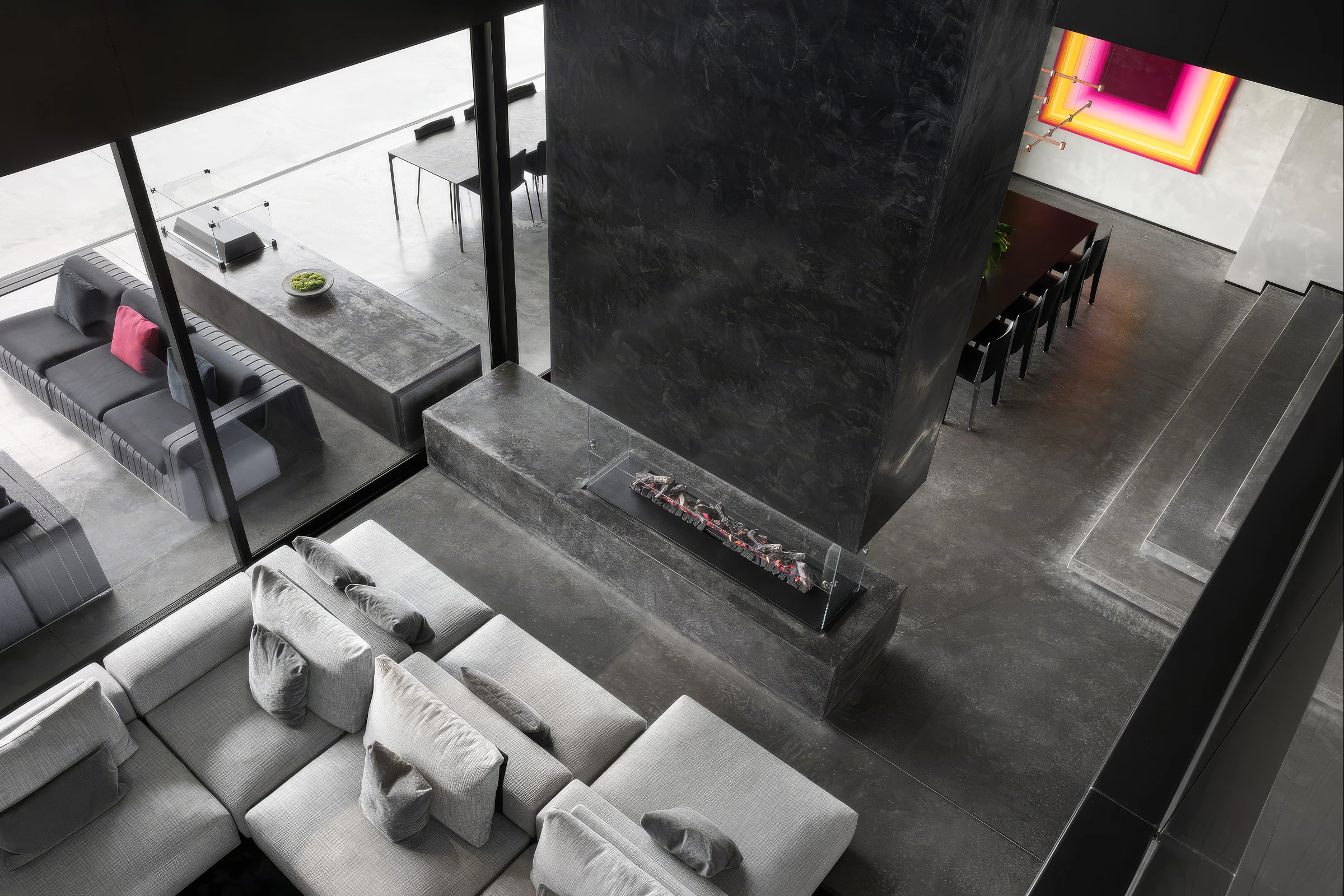 Open-plan living area and dining room with concrete floors and central fireplace