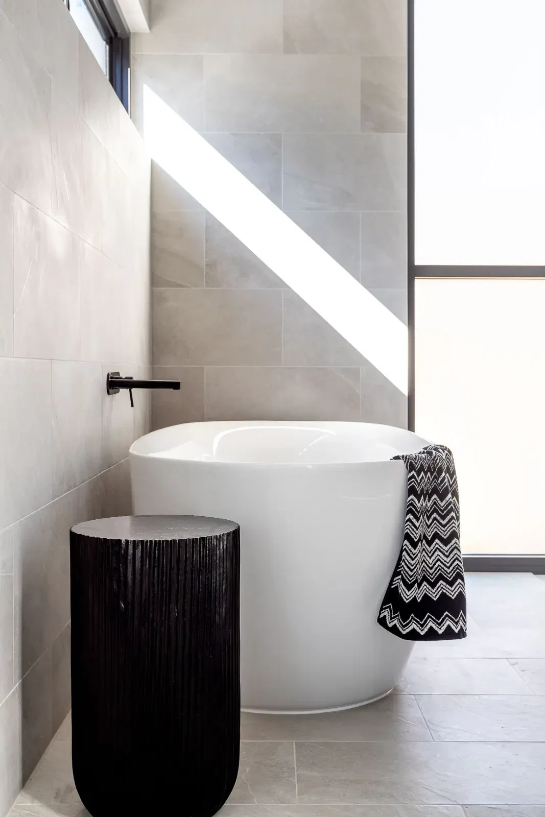 Modern bathroom with freestanding bathtub and black textured side table