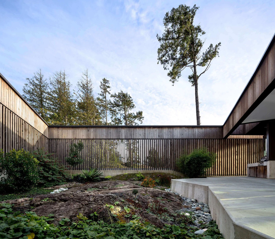 Wooden courtyard with concrete seating area and surrounding greenery