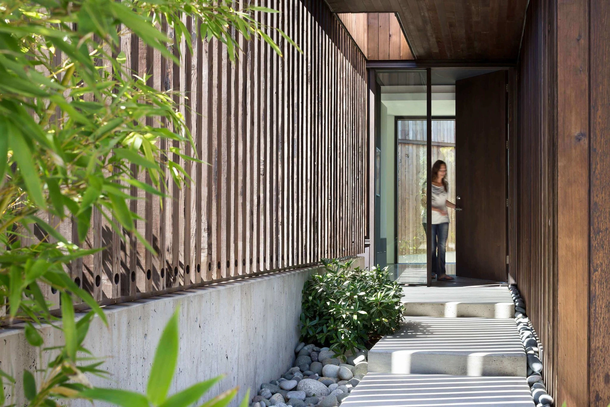 Entrance area of modern house with wooden cladding and landscaped garden pathway