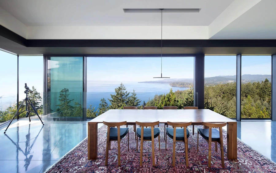 Dining room with large windows overlooking a coastal landscape