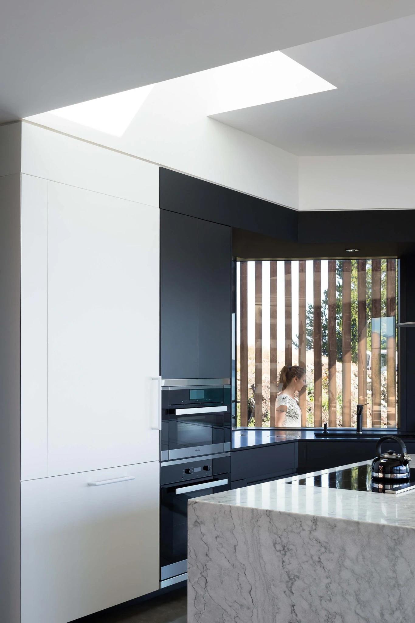 Kitchen interior with black and white cabinetry and a marble island