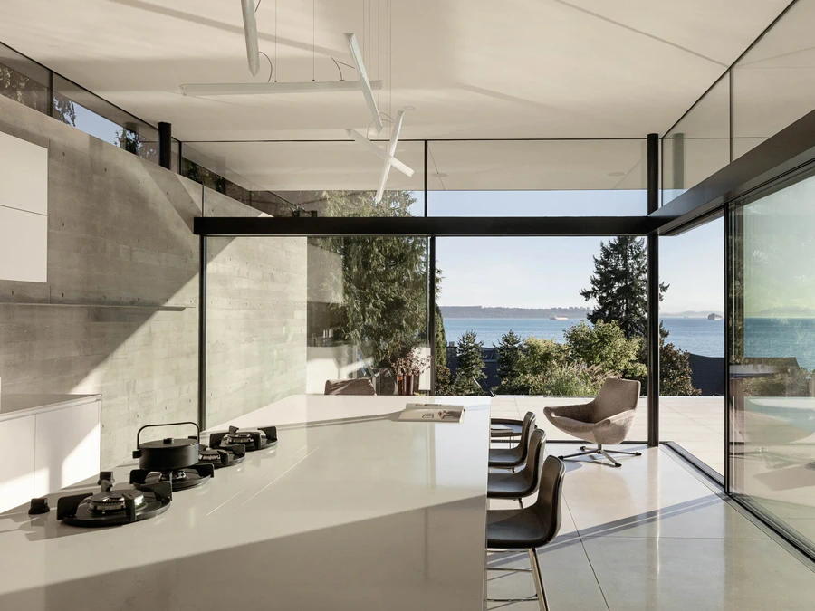 Open plan kitchen with large windows overlooking ocean and trees