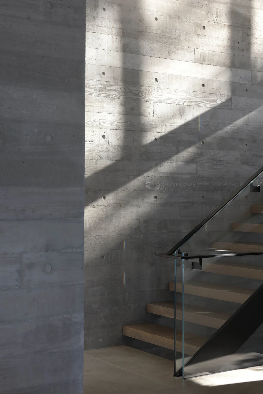Concrete wall and timber staircase with glass balustrade