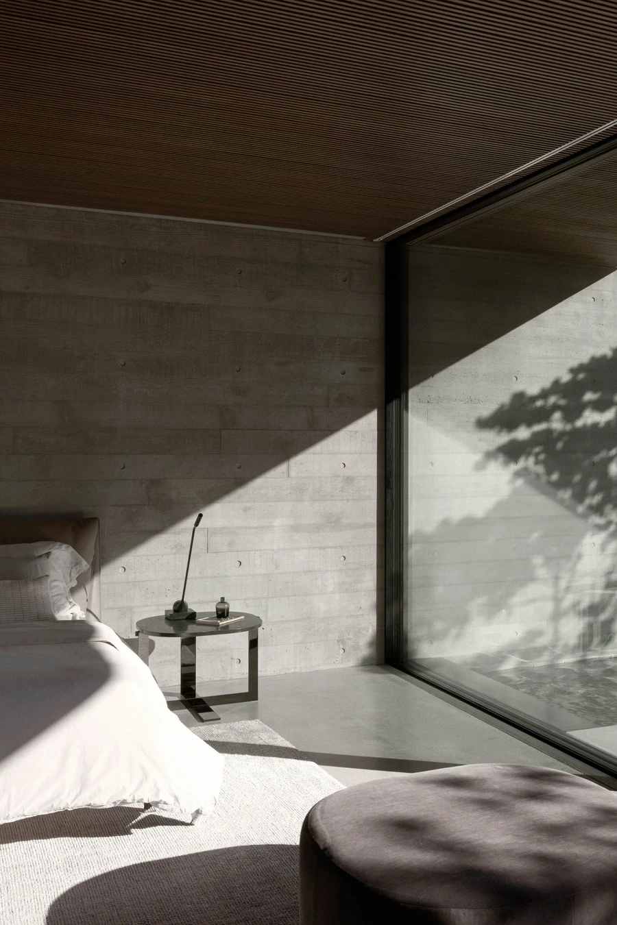 Minimalist bedroom with concrete walls and large floor to ceiling window