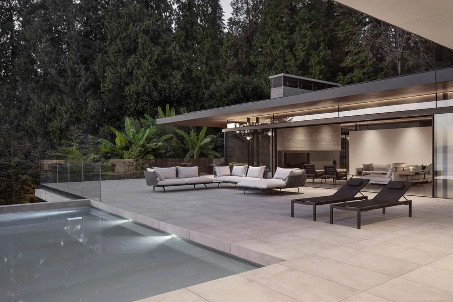 Outdoor patio next to swimming pool and glass-walled house
