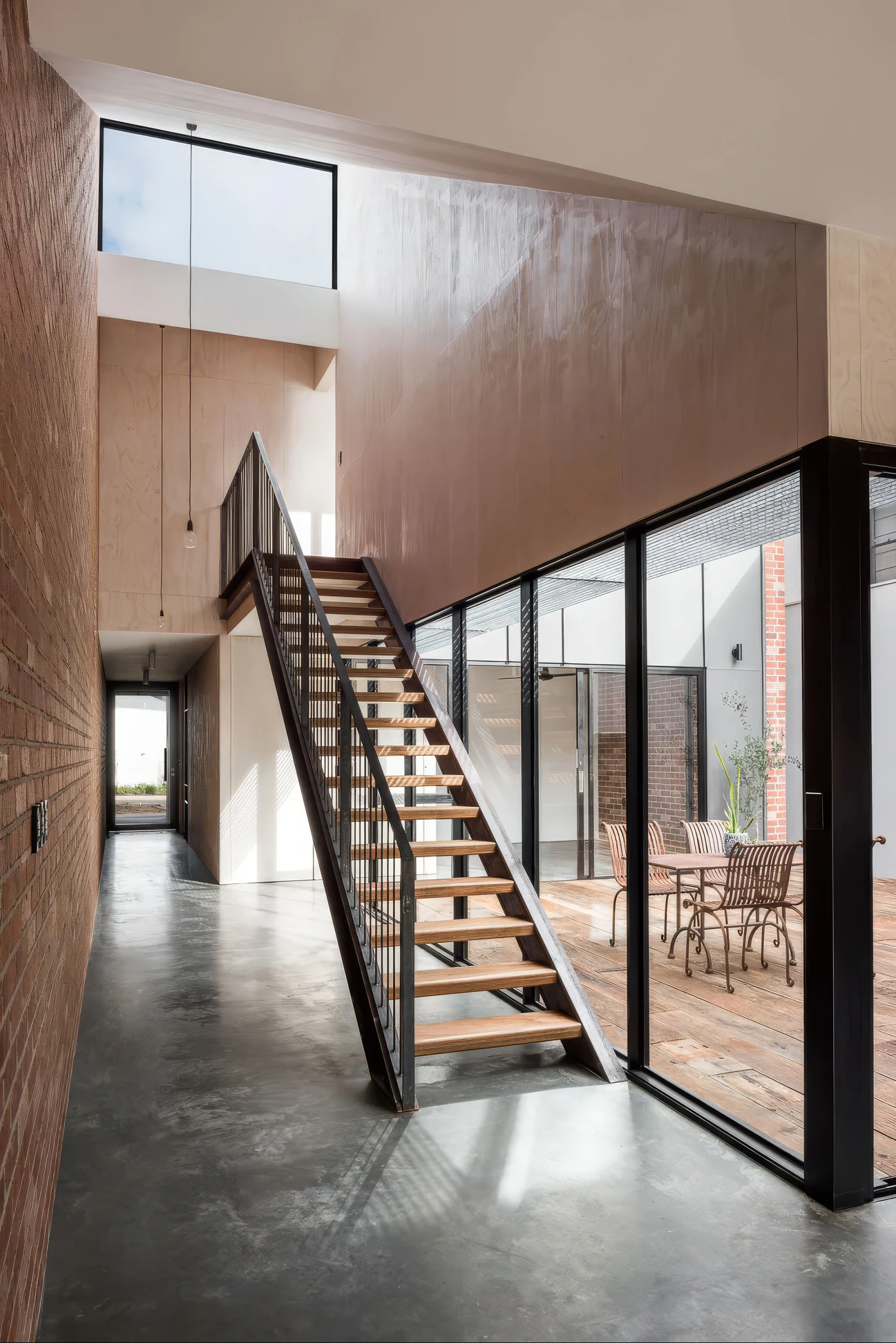 Brick hallway, polished concrete floor and steel stair courtyard glazing