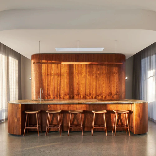 Curved wooden kitchen island and bar stools in the Kira House's kitchen