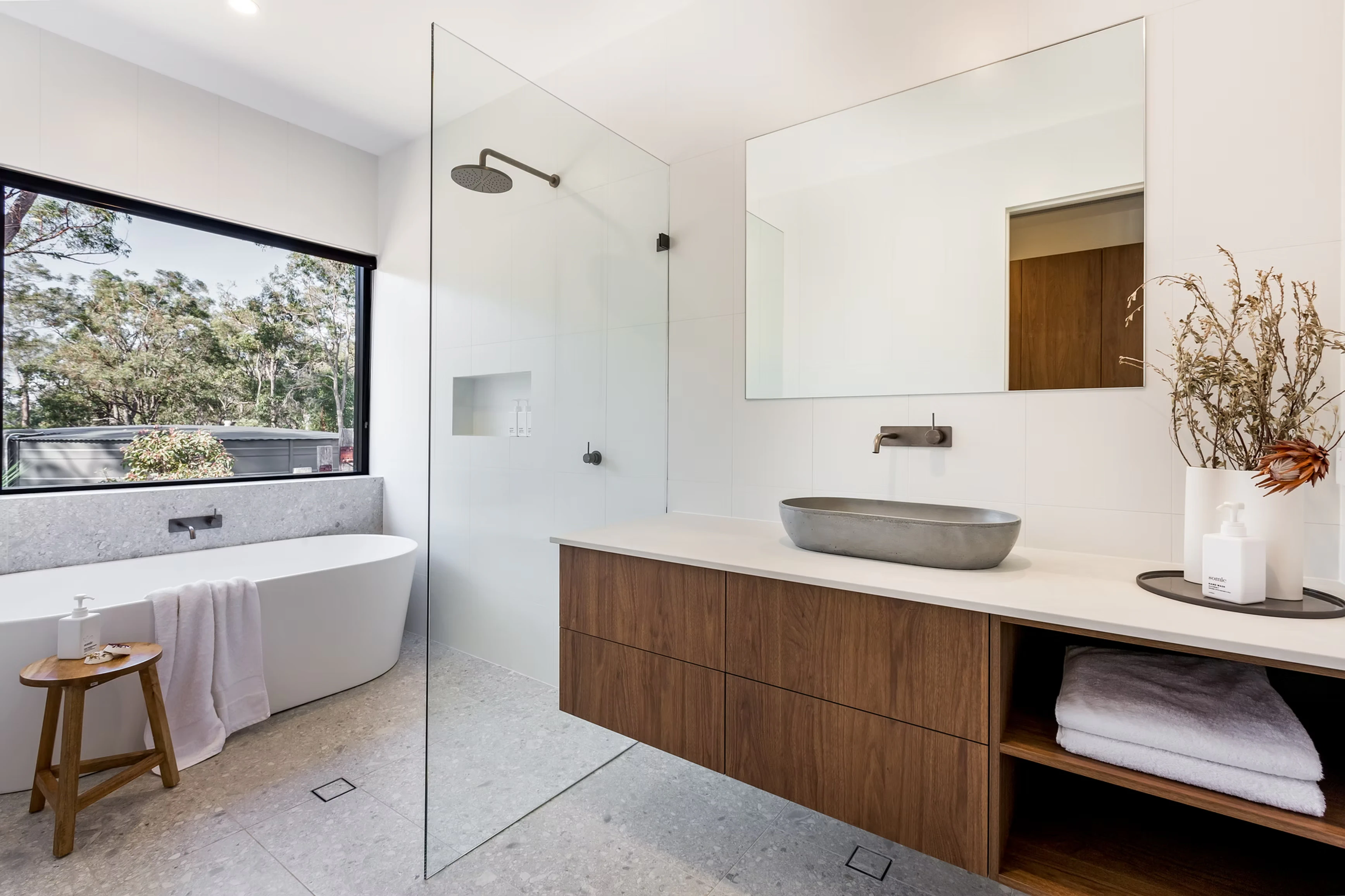 Modern minimalist bathroom with freestanding bathtub, walk-in shower, and wooden vanity