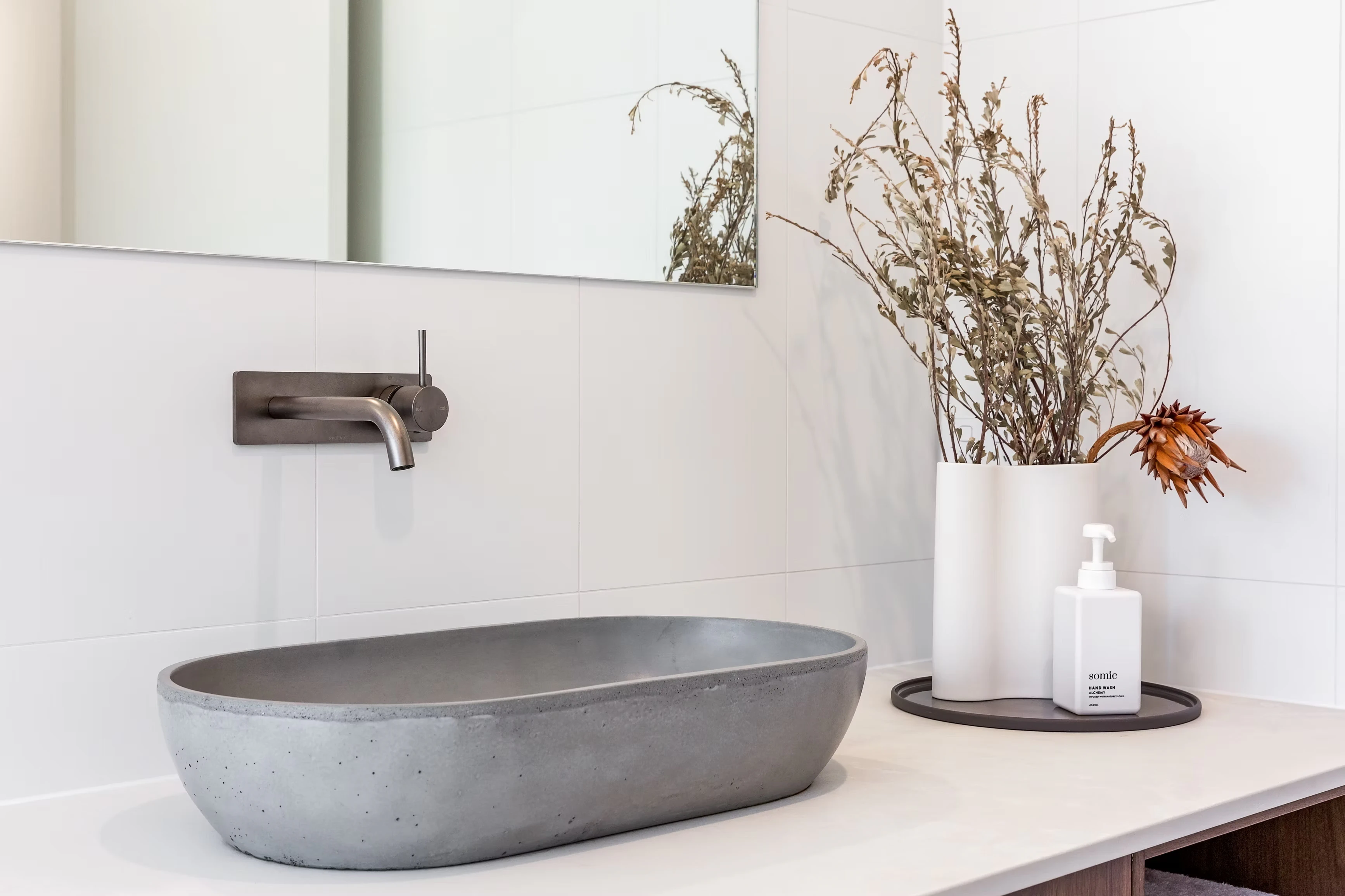 Concrete vessel sink on bathroom vanity with wall-mounted faucet and decorative vase