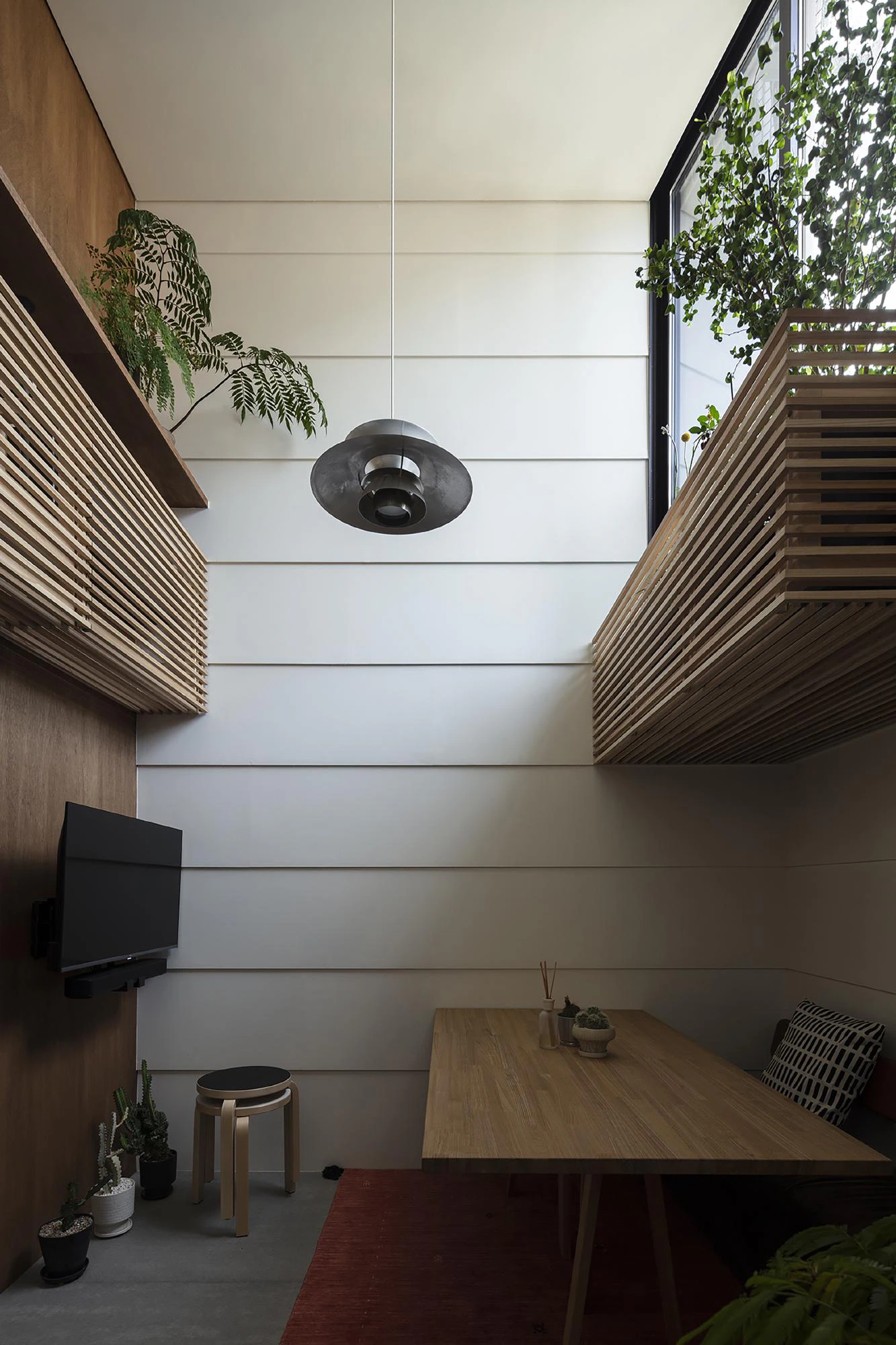 Vertical machiya interior void, timber slatted platforms and dining area