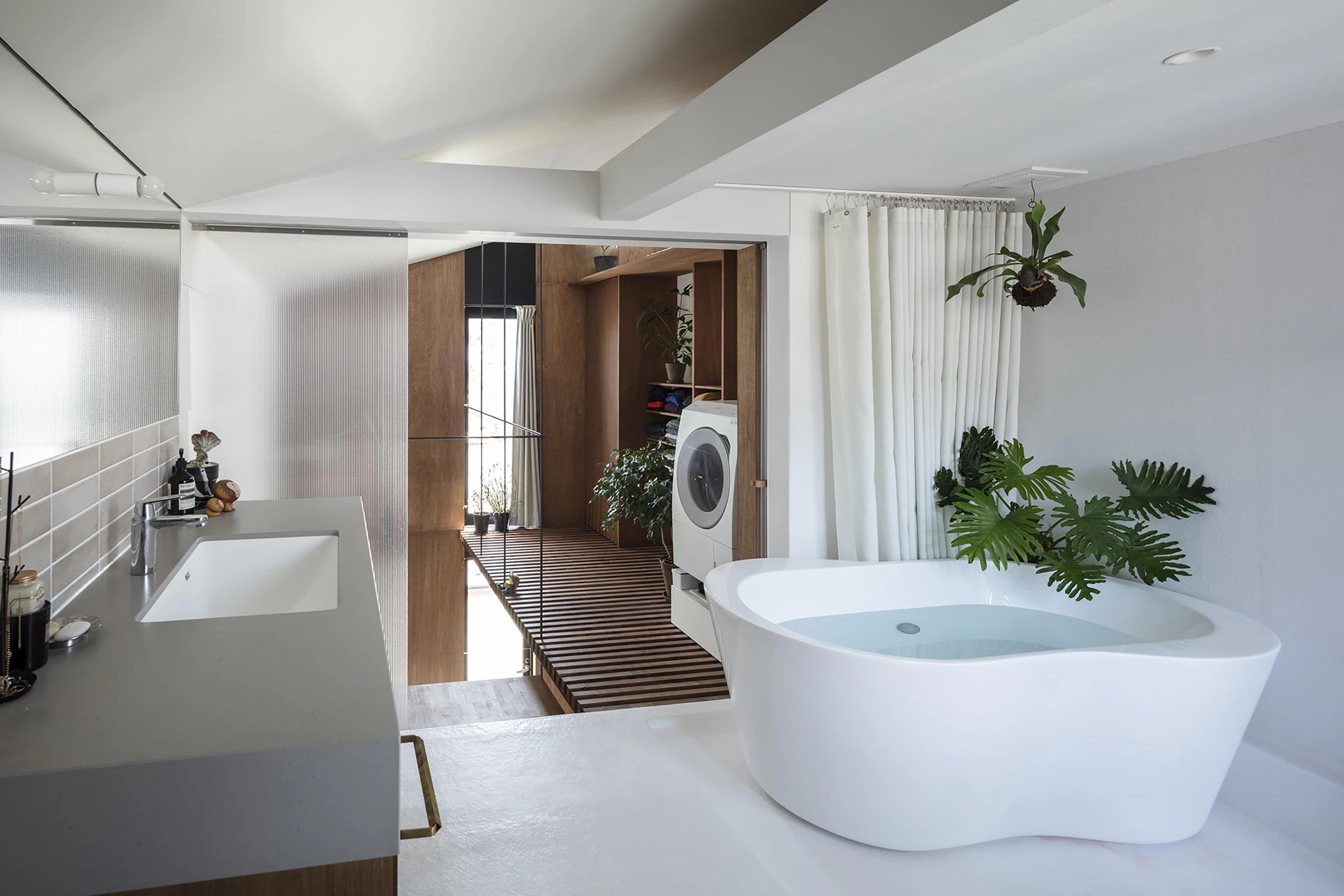 Compact Tokyo bathroom, freestanding bath and timber laundry storage