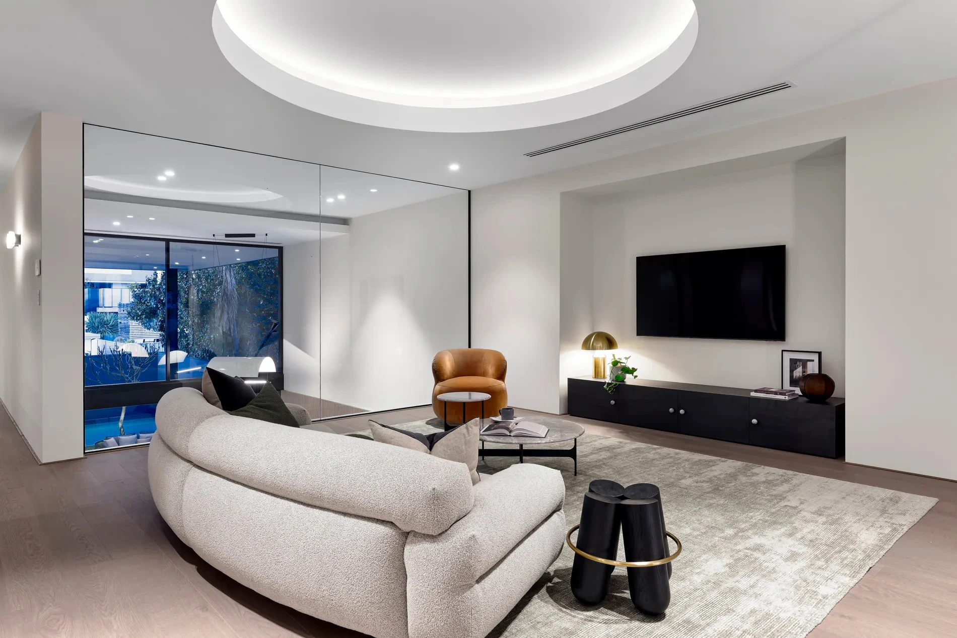 Modern living room with a curved sofa, wall-mounted TV, and minimalistic decor