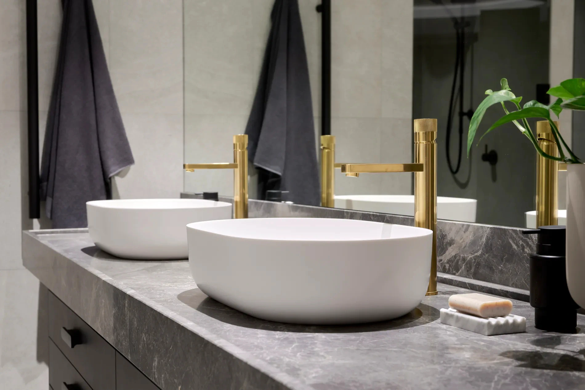 Bathroom countertop with two vessel sinks and gold faucets