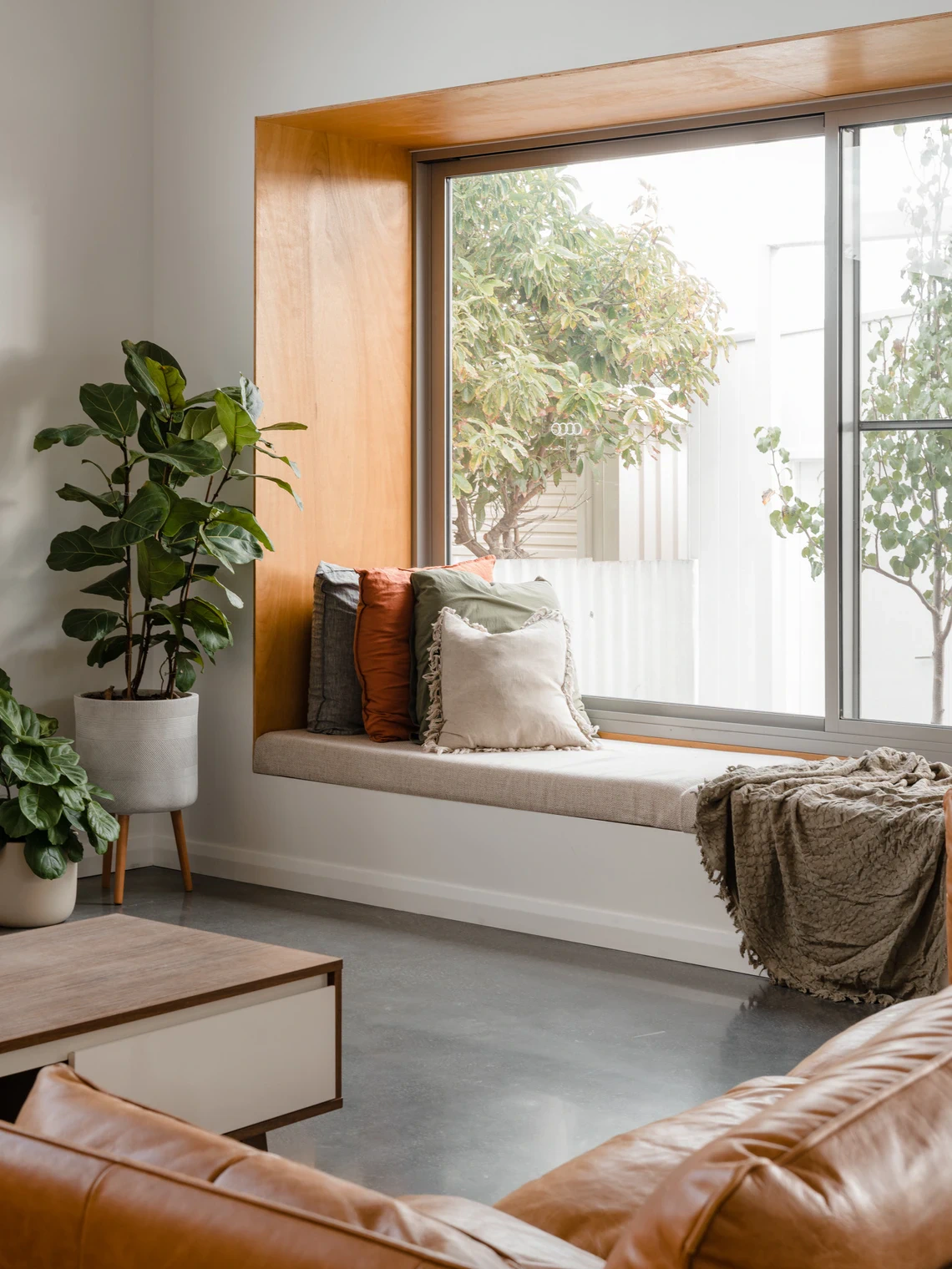 Living room window seat with pillows and indoor plants