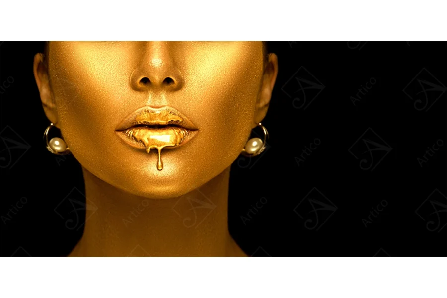 Articoo - A model's face with metallic gold skin makeup and lip gloss dripping with gold liquid - Articoo-945161
