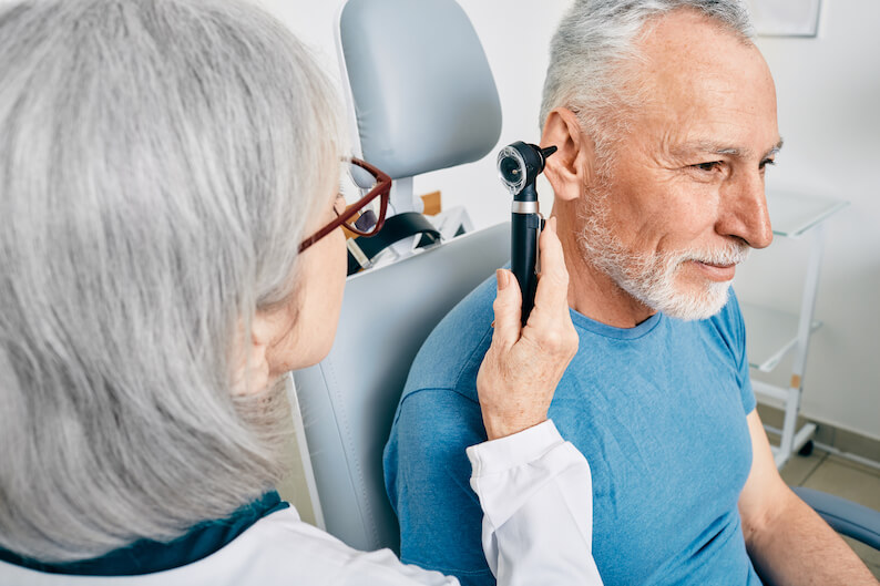 Older adult man suffering from tinnitus getting his ears checked