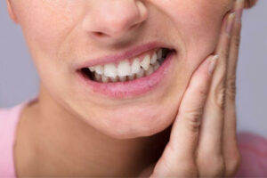 woman dealing with tooth sensitivity due to loss of enamel from acidic saliva.