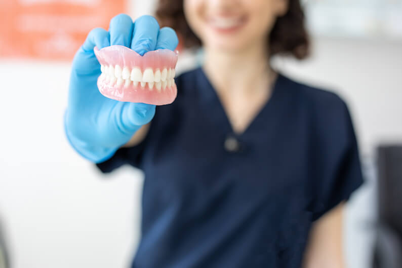 dentist holding dentures a treatment for edentulism