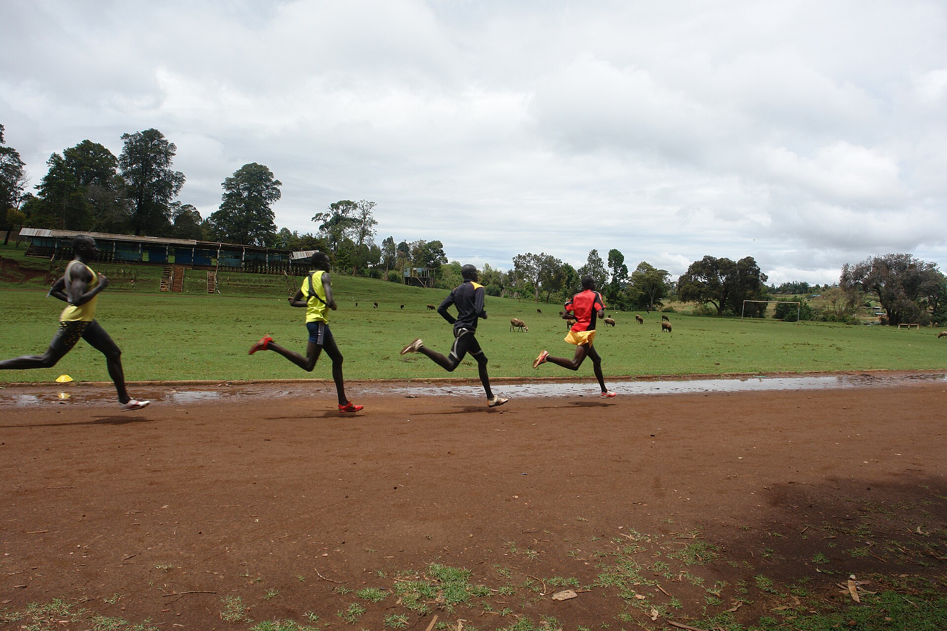 Four athletes running on the red-dirt track at Iten, Kenya