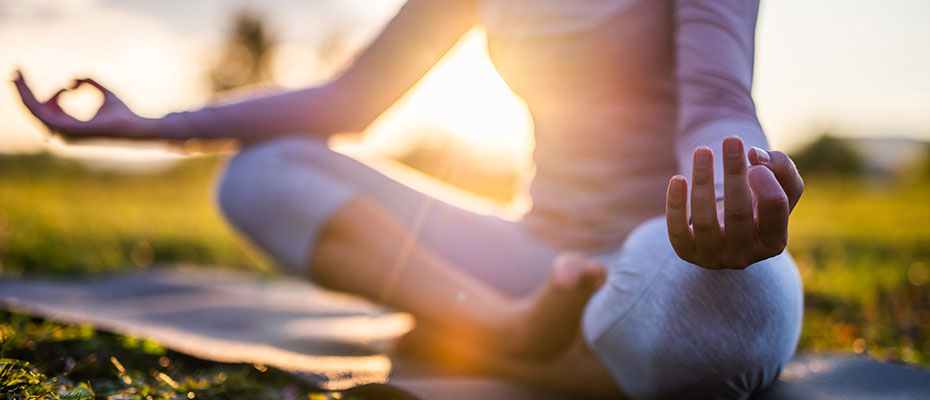 A woman meditating outside on a yoga mat