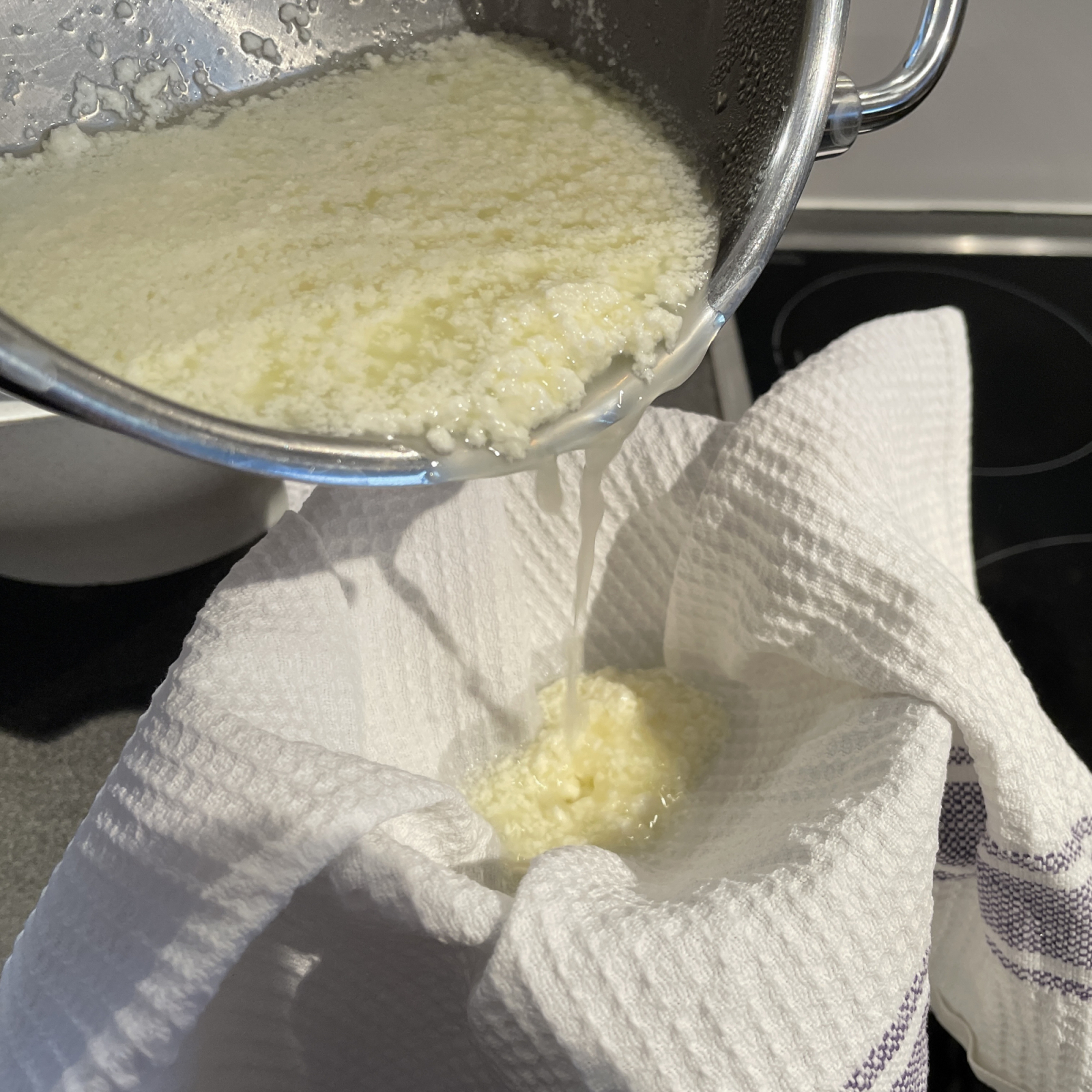 Der Frischkäse oder auf indisch Paneer-Käse wird in ein Tuch abgeseiht und dann mit einem gefüllten Topf gepresst