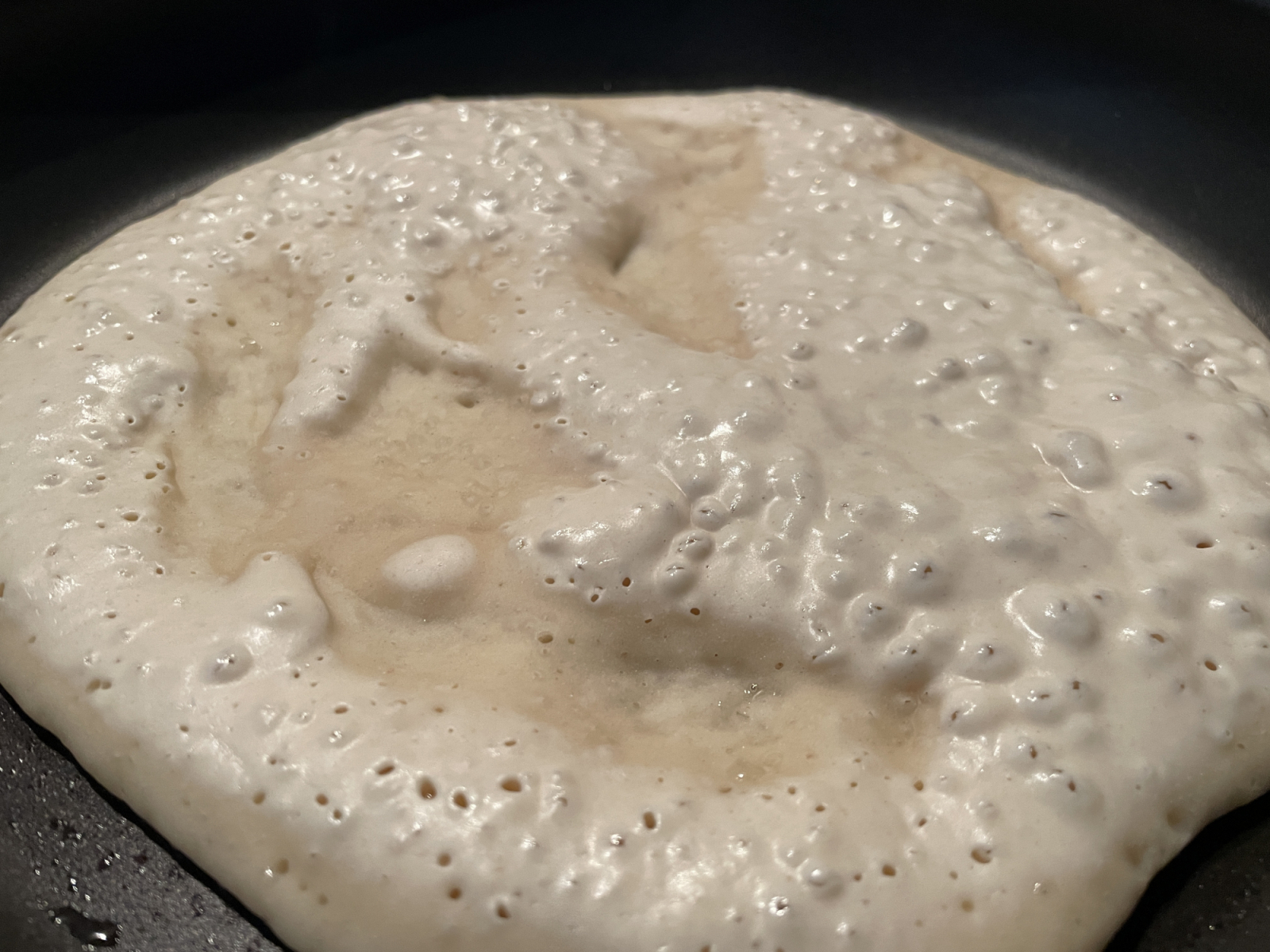 Der Teig fürs gefüllte Pfannenbrot wird langsam durch, wenn Bläschen aufsteigen